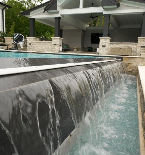 Waterfall feature in backyard with a pool and outdoor patio area