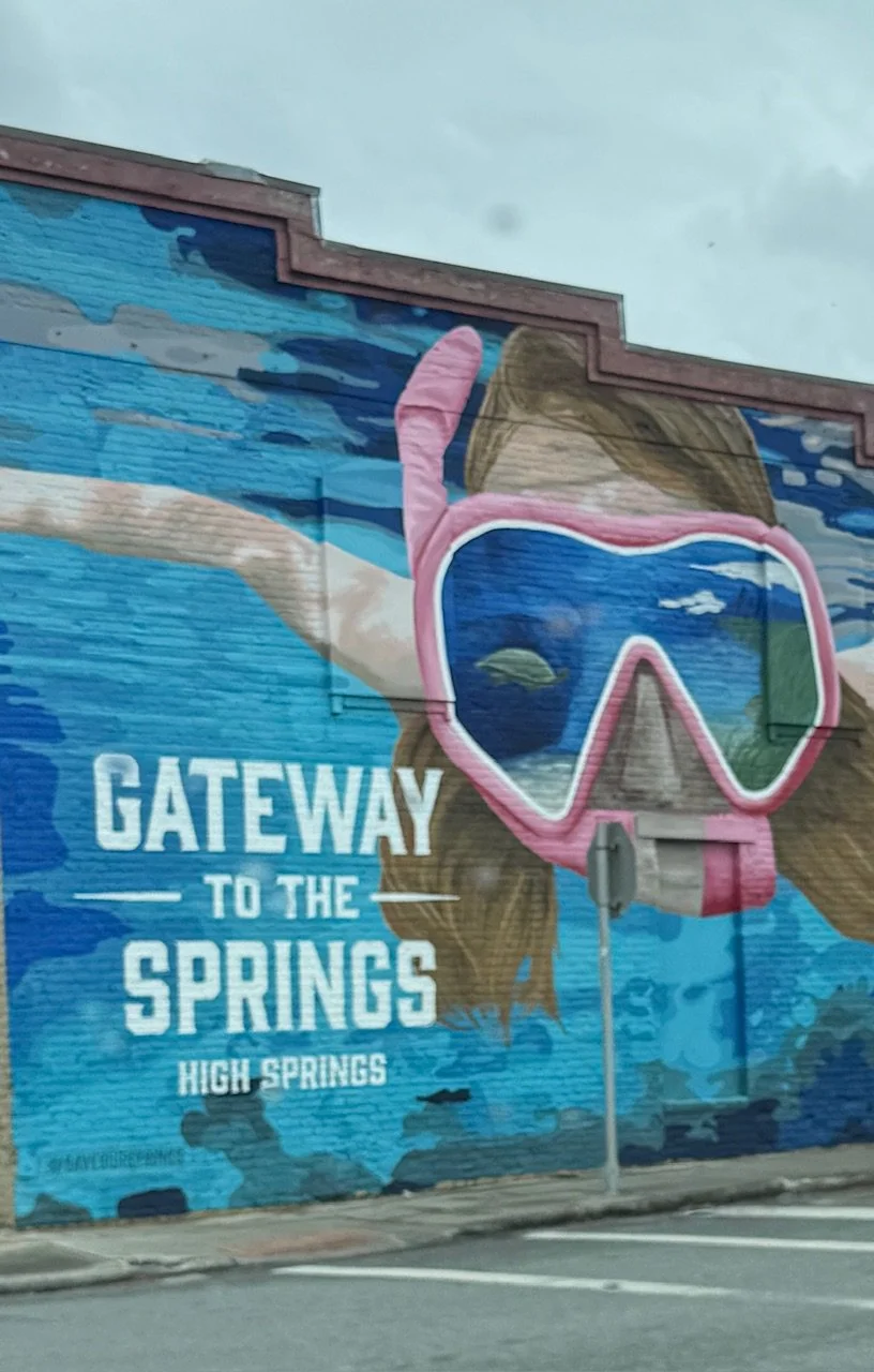 Mural painting on a building wall depicting a person snorkeling with goggles, with the text "Gateway to the Springs, High Springs".