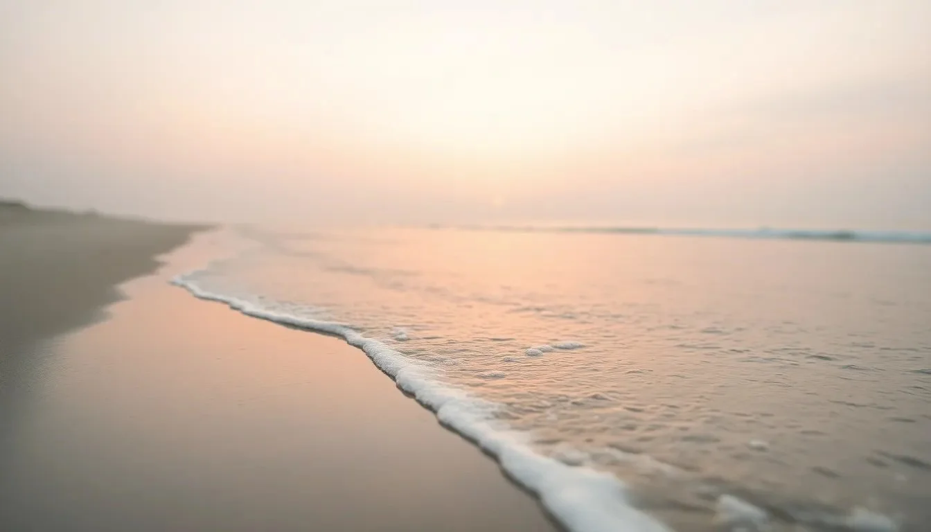 Softly crashing ocean waves on a sandy beach at sunset with pink and purple skies.