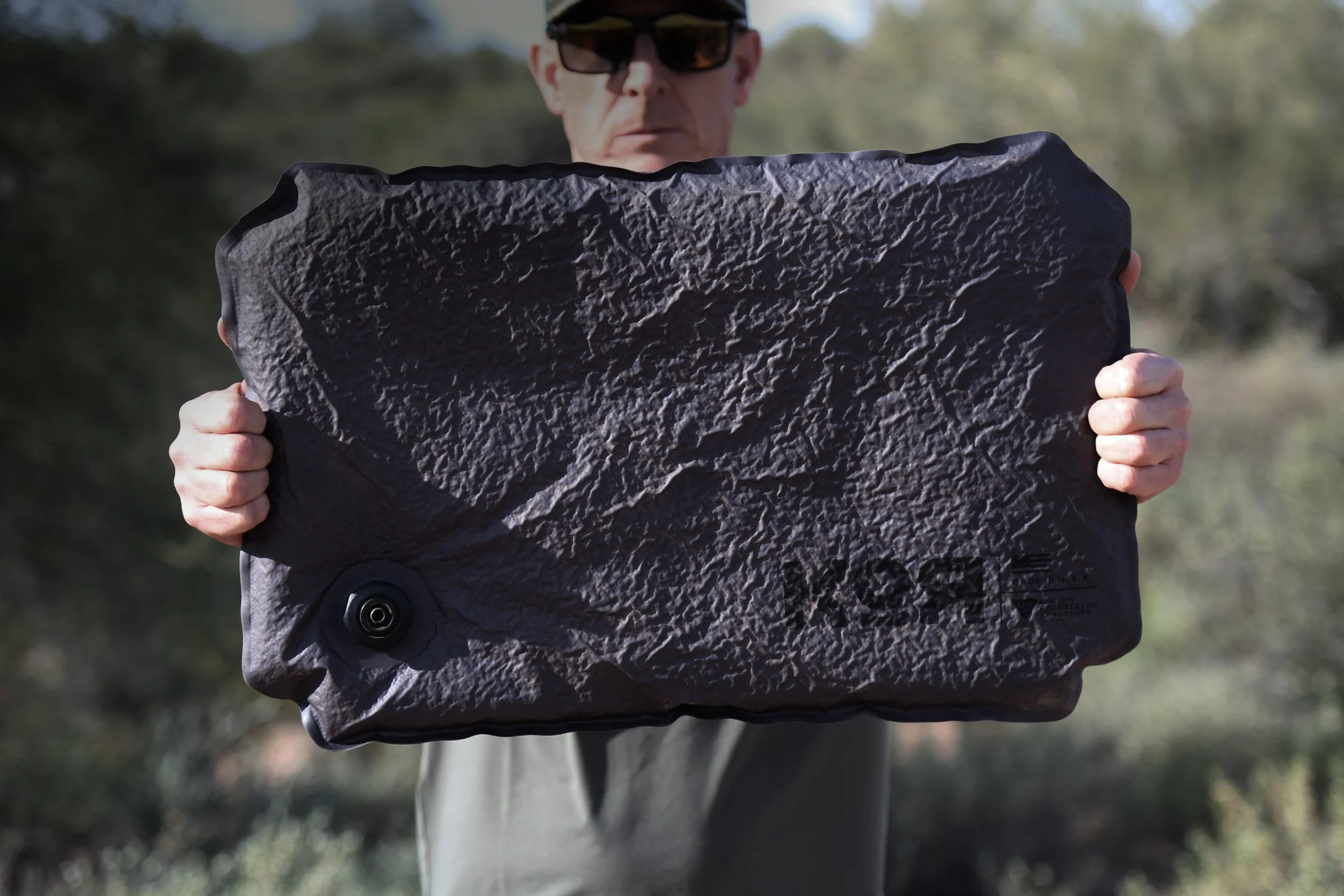 Person holding a KOR Single Panel featuring patented Vacuum Rigidizing Structure (VRS) technology for customizable equipment protection.