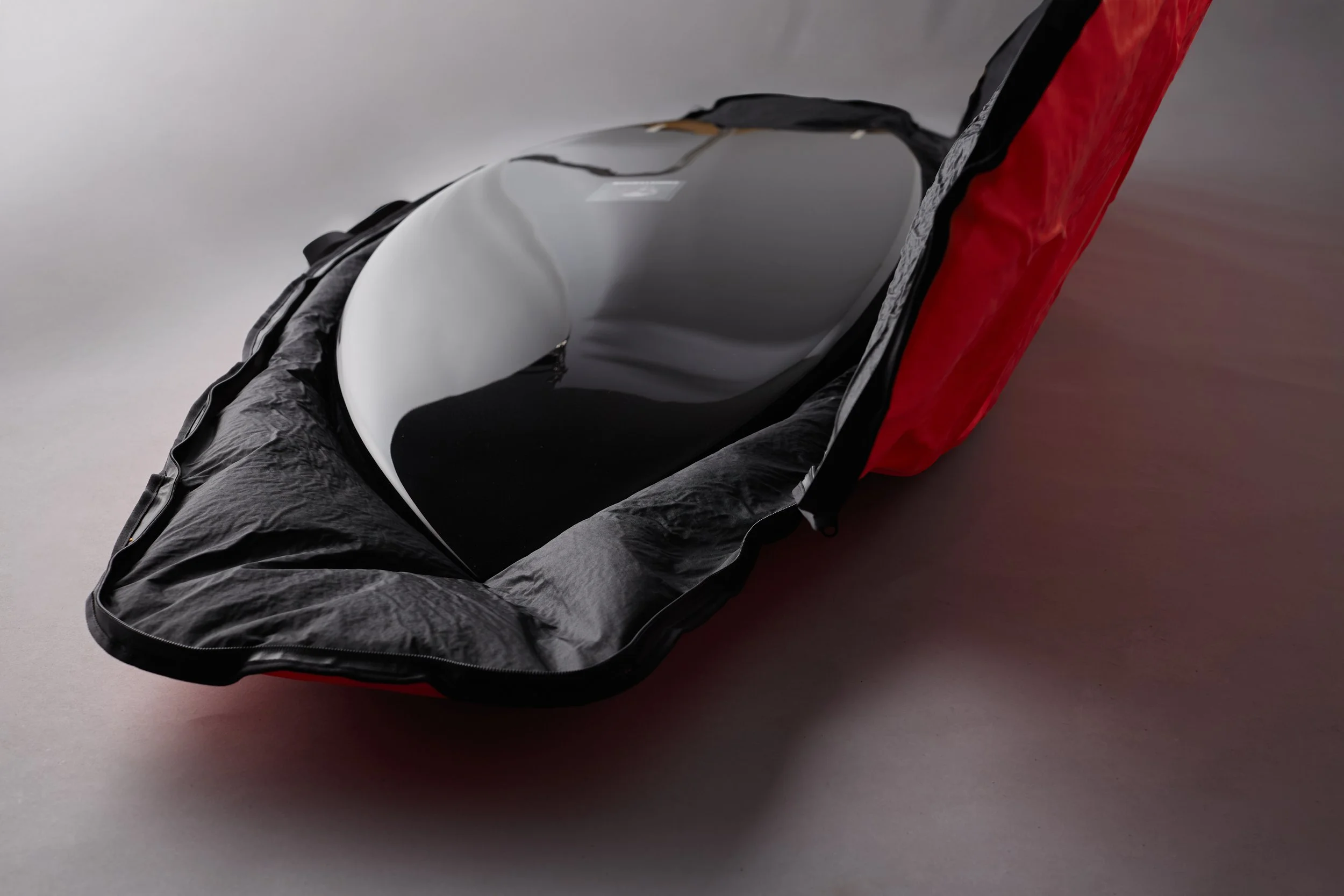 Close-up image of a black and gray lounge chair with a red cloth covering the backrest, placed on a gray surface.