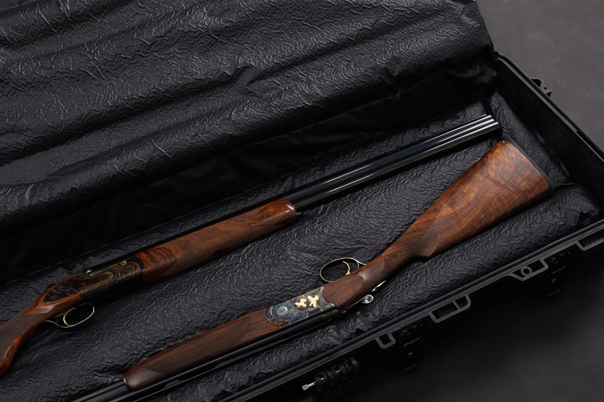 Shotgun with a wooden stock placed inside a black protective case lined with textured black material.