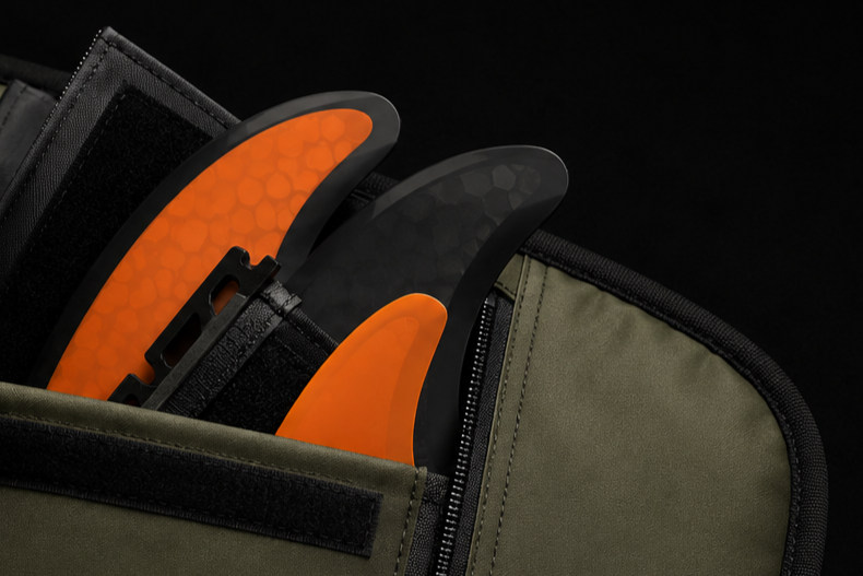 Close-up of two surfboards in a bag with black and orange, orange and black fins.