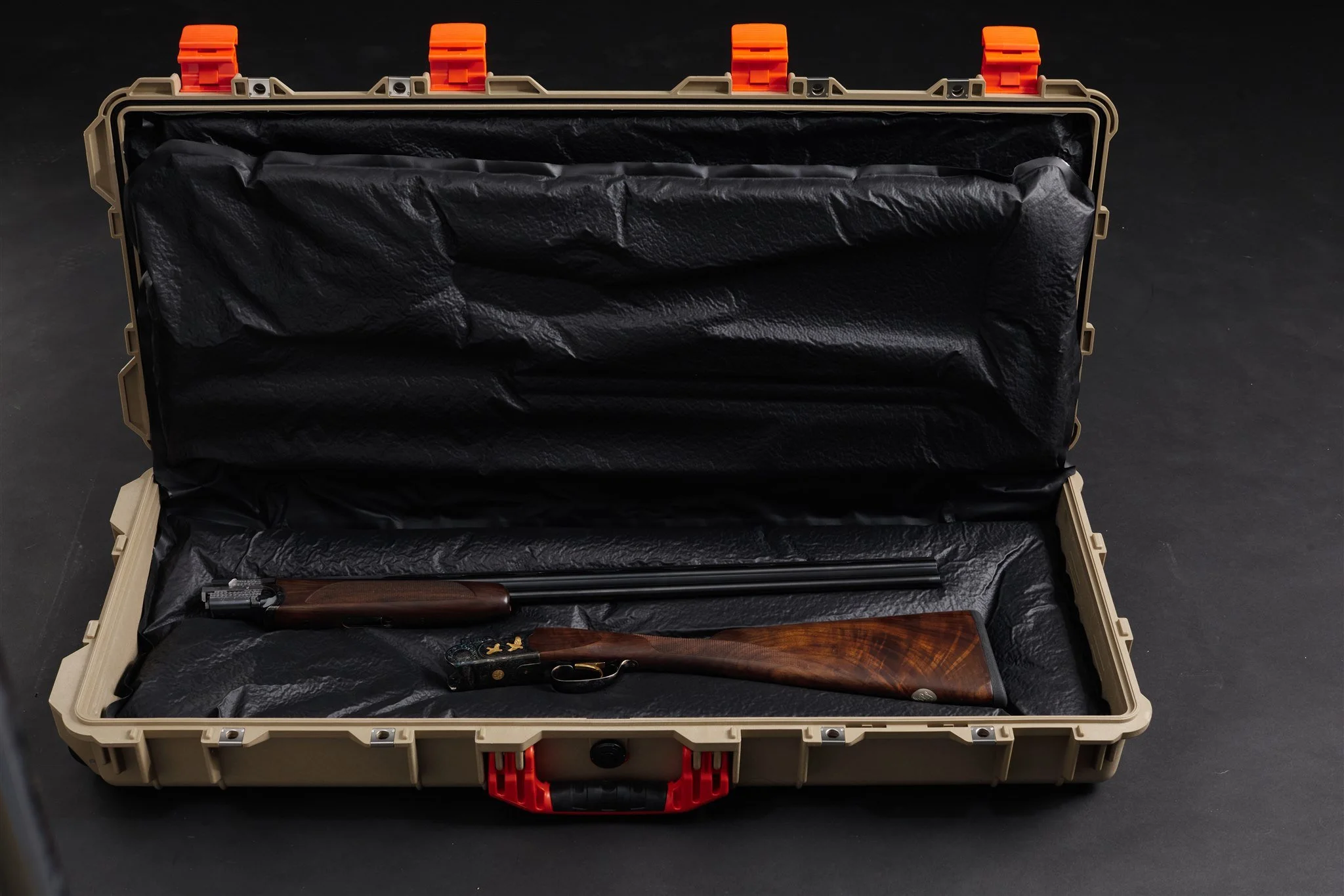 A rifle with a wooden stock and black barrel inside an open beige protective carrying case lined with black foam padding.