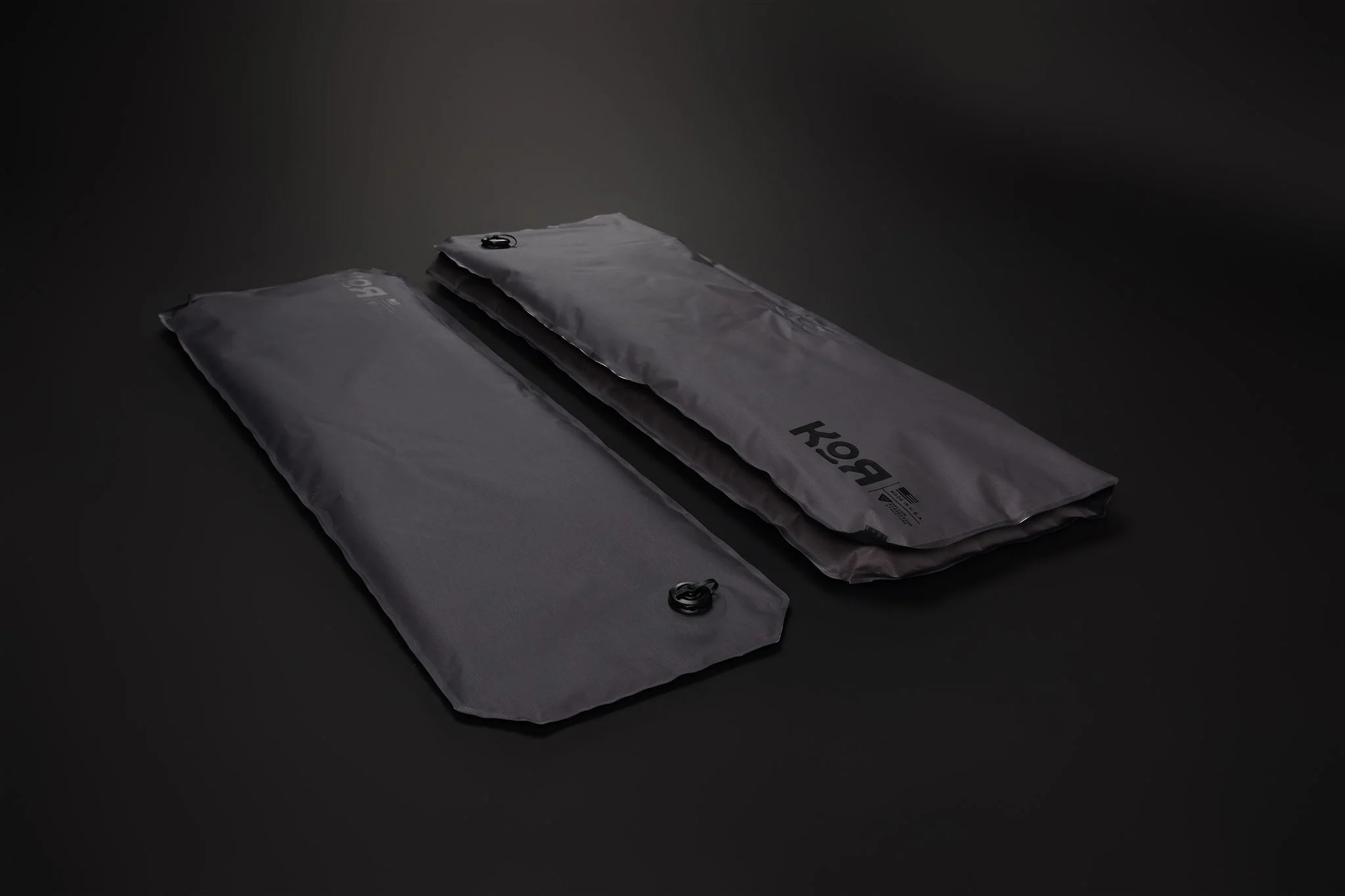 Two gray, sealed rectangular packages with black circular zip ties on dark background.