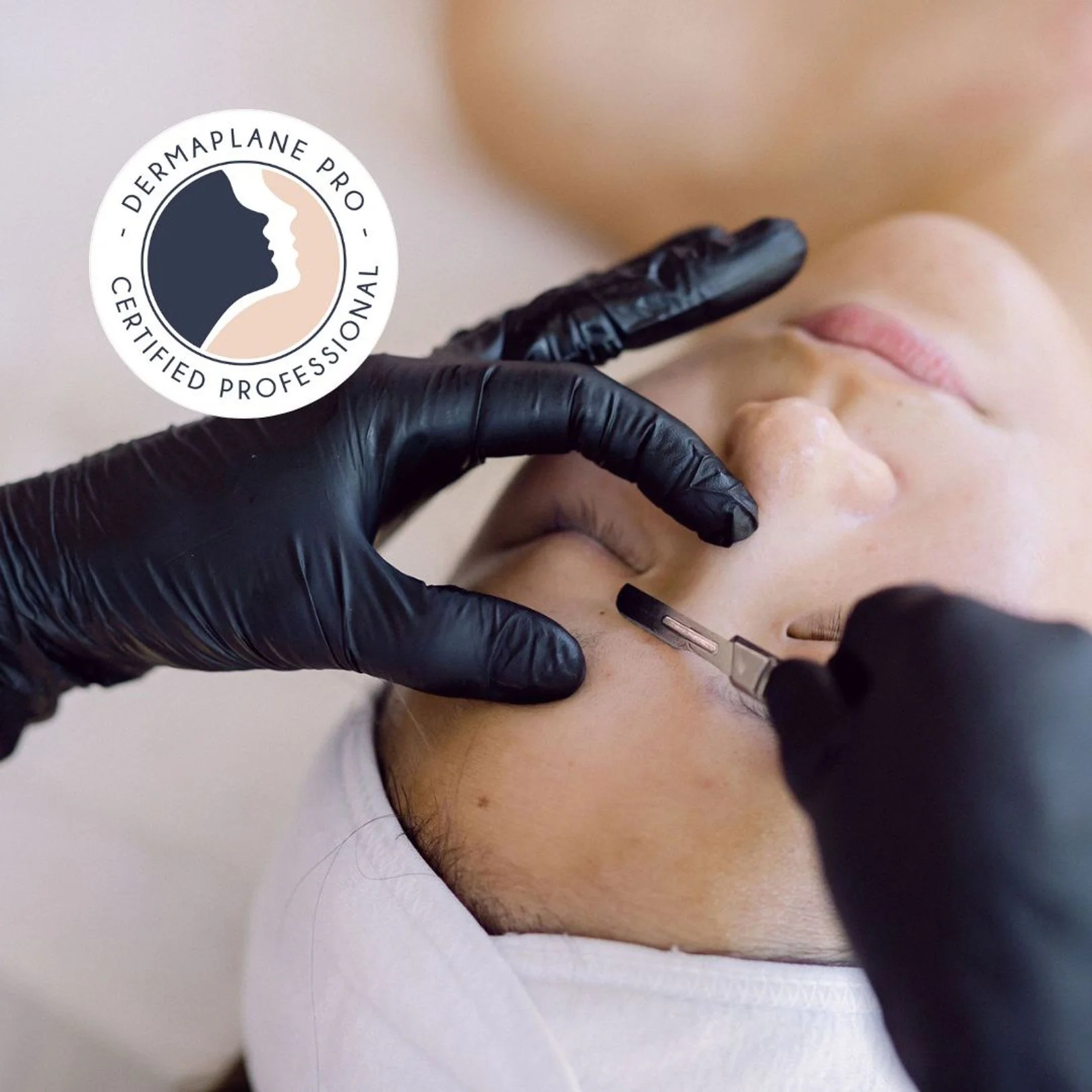 Person receiving a facial treatment with a tool injected into their skin while wearing a white headband, held by a technician wearing black gloves.