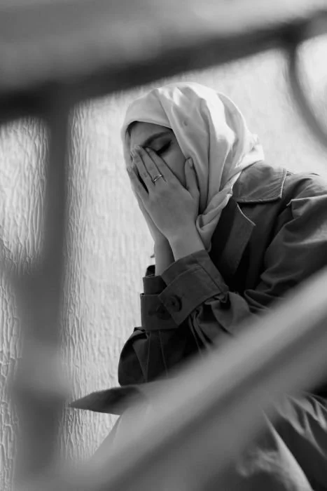 Woman wearing a hijab sitting with her hands over her face