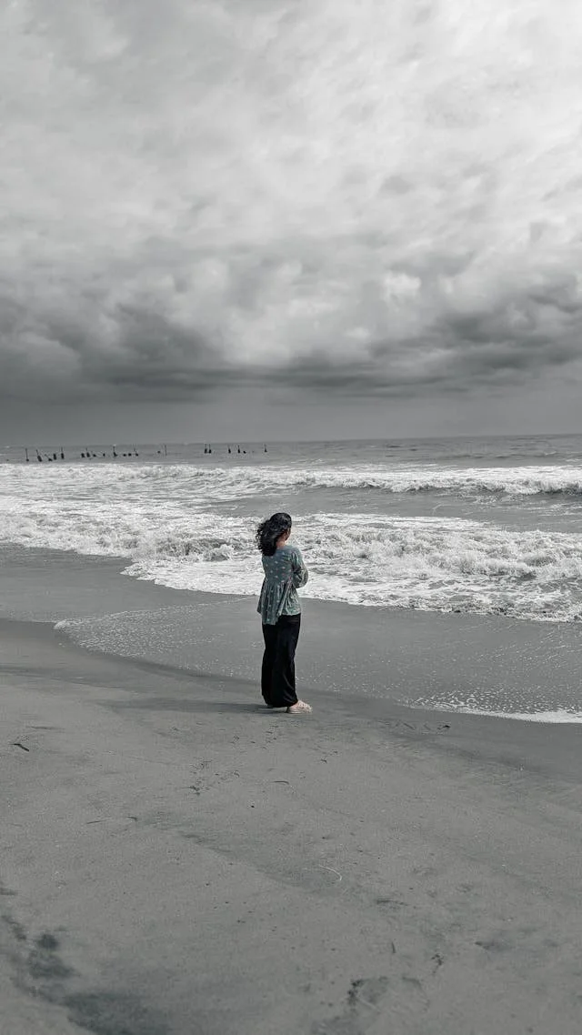 woman standing alone on grey beach