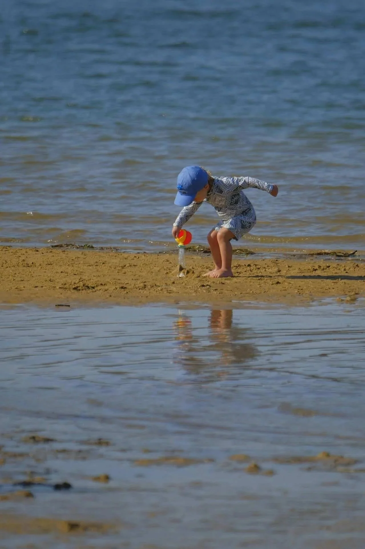 child playing with water on beach