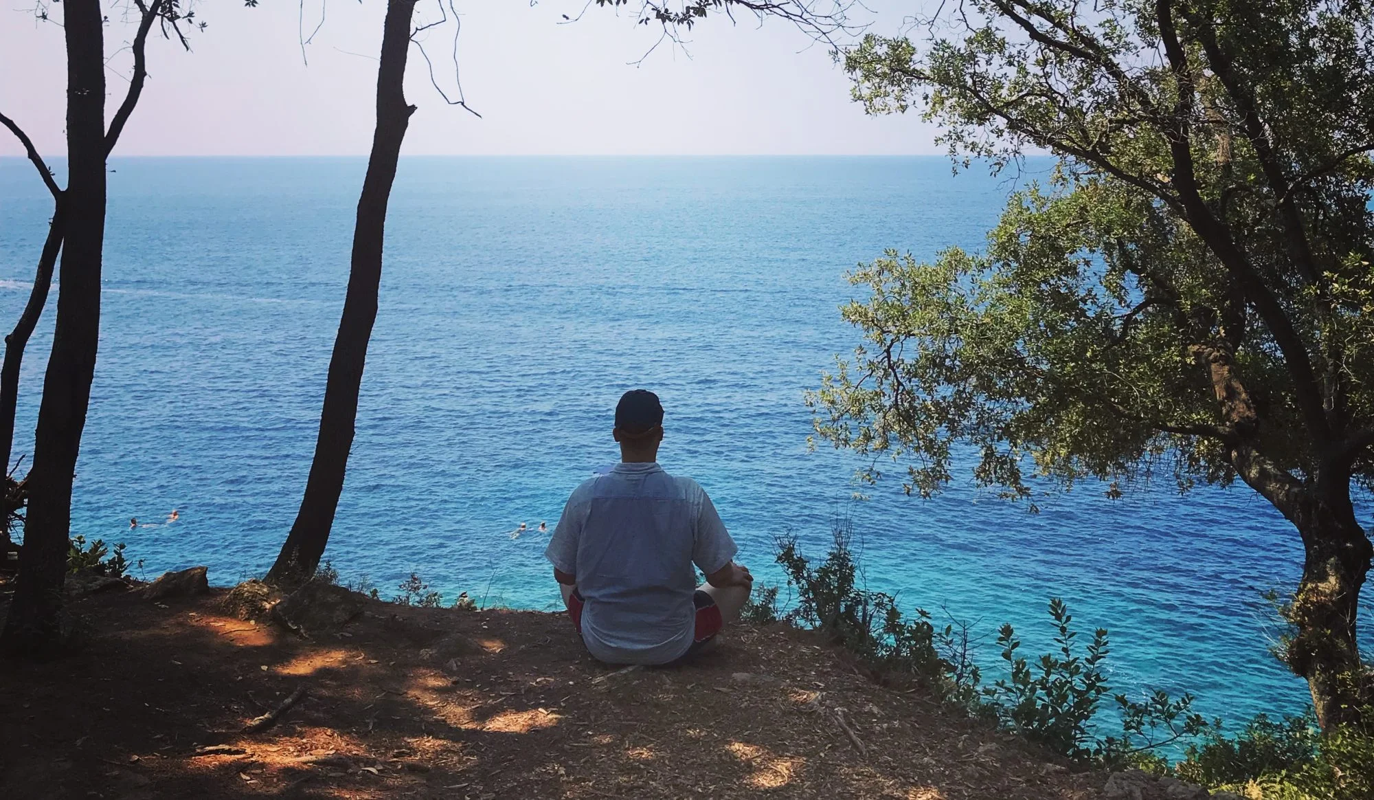 Man sitting on overlook meditating above water