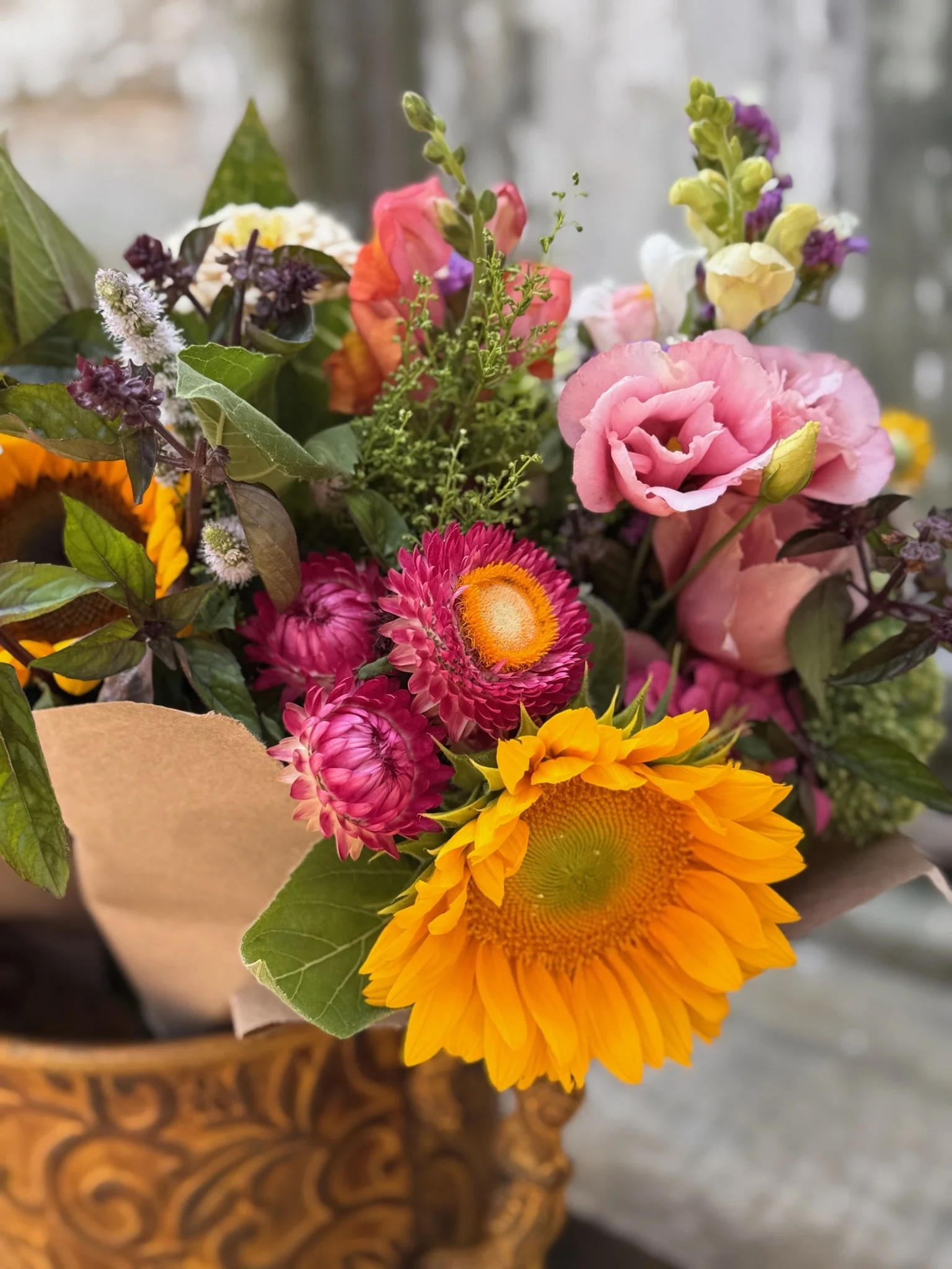 Colorful bouquet of various flowers including sunflower, pink roses, and other blooms in a decorative vase.