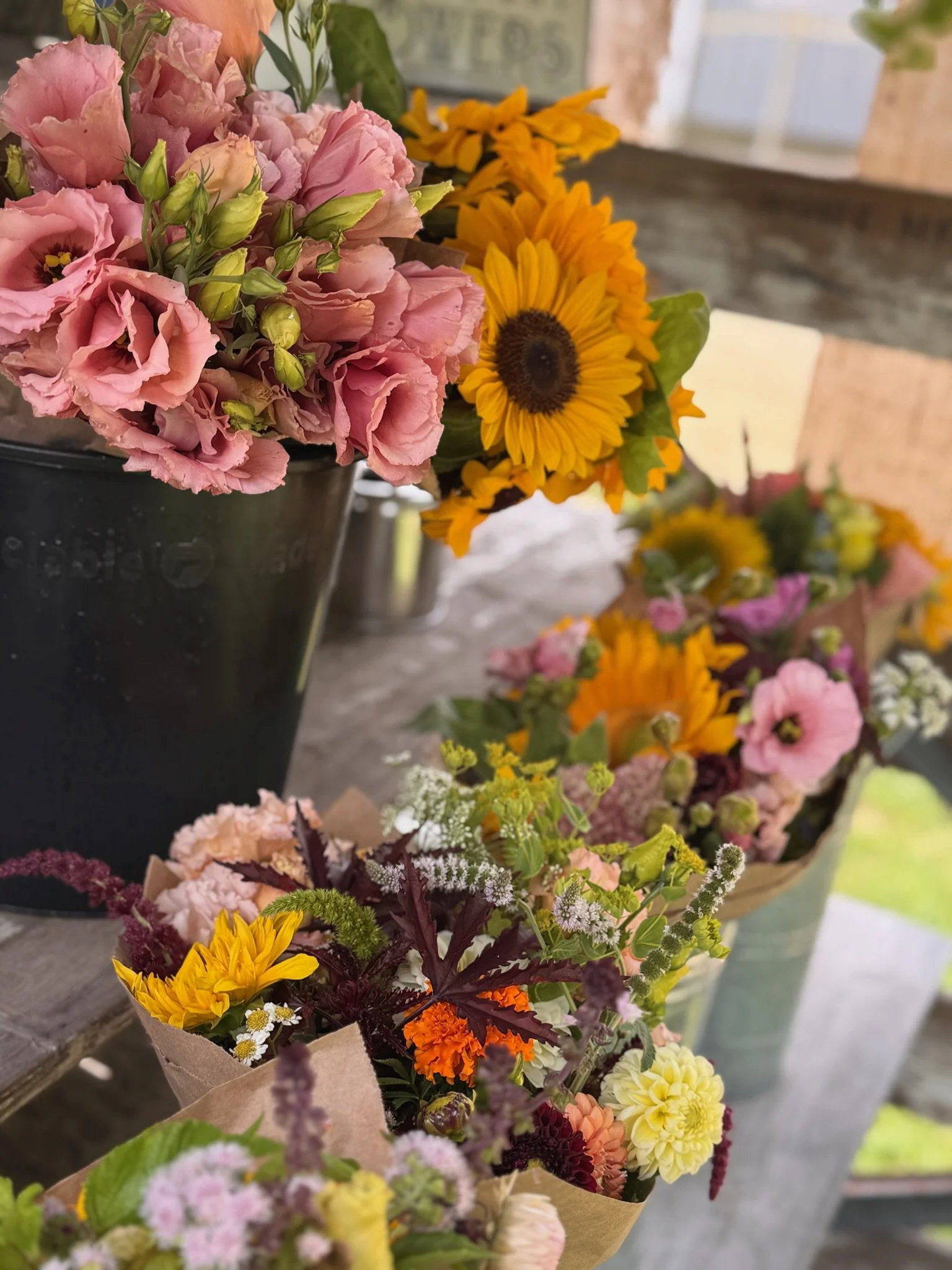 Colorful bouquets of fresh flowers, including pink, yellow, purple, and white blossoms, arranged on a rustic wooden surface.