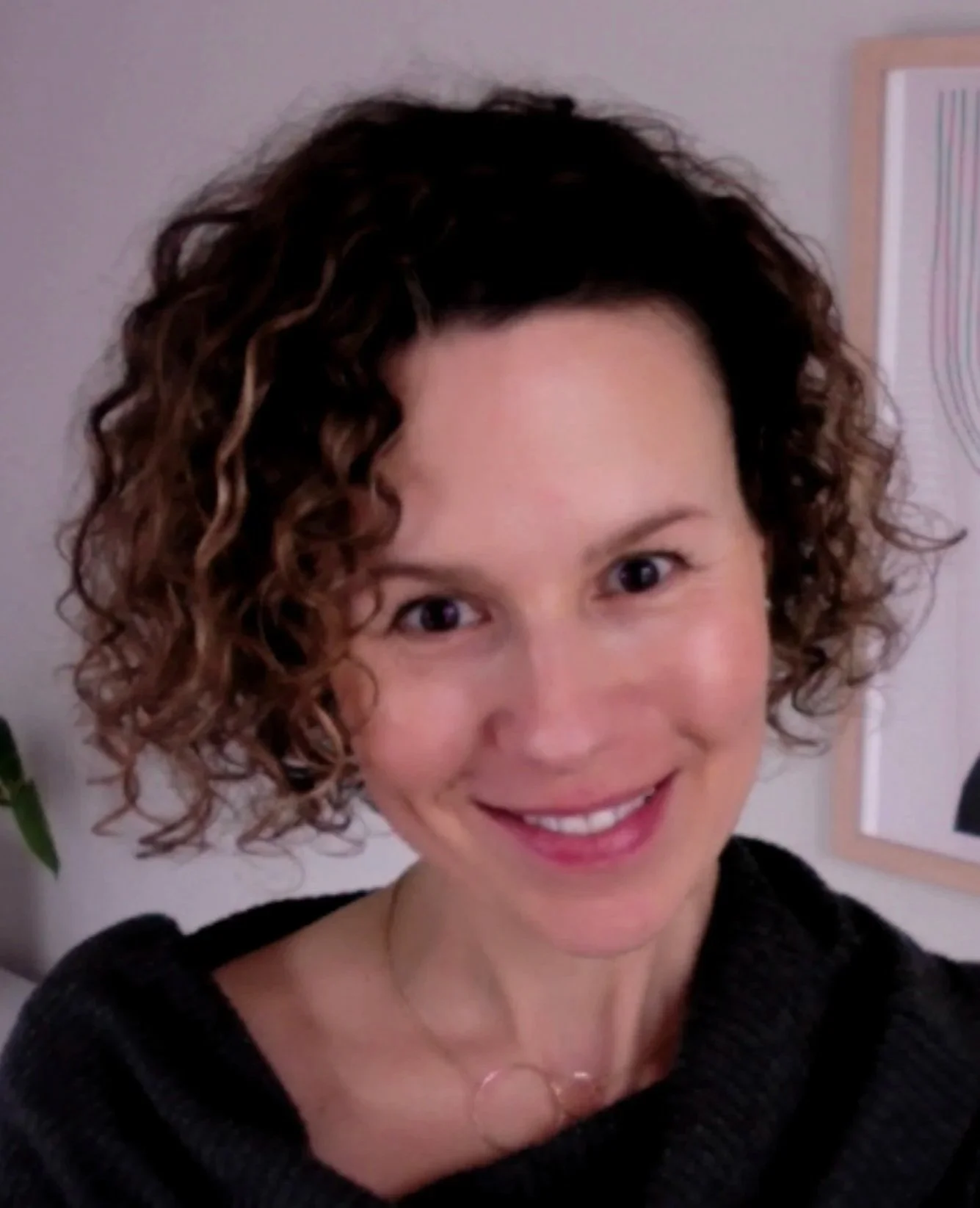 Close-up of a smiling woman with short curly hair wearing a black top.