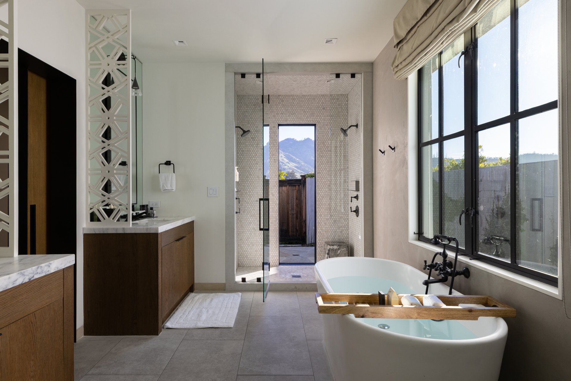 Modern bathroom with a freestanding bathtub, a large window, a walk-in shower, and wooden accents.
