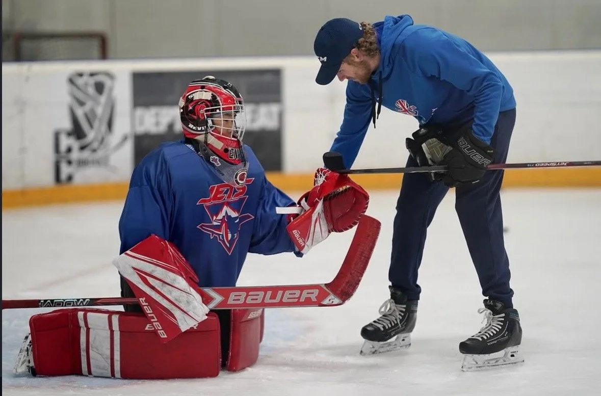 Hockey coach talking to goaltender on ice rink