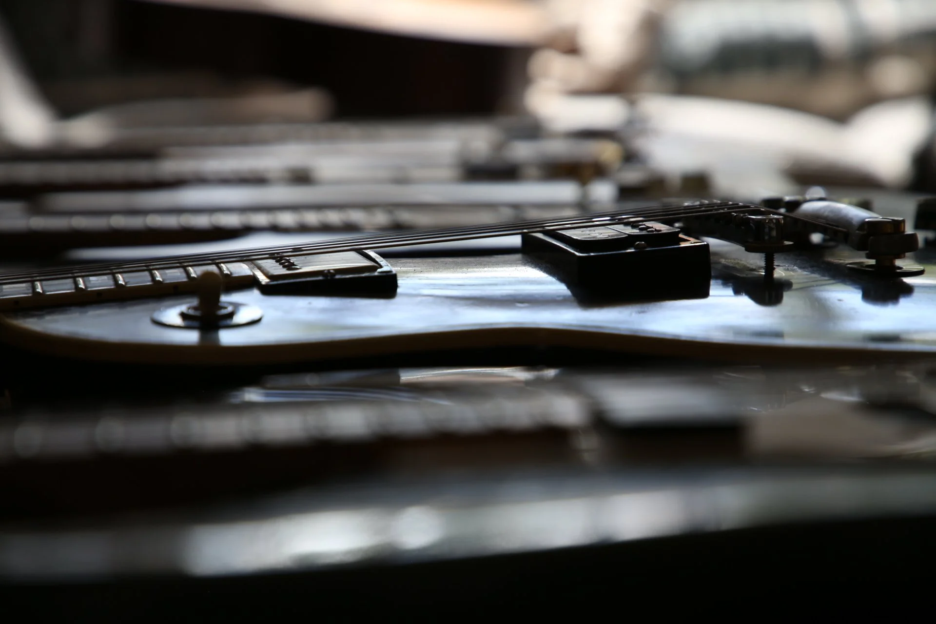Close-up of an electric guitar's fretboard and strings, with a blurred background.
