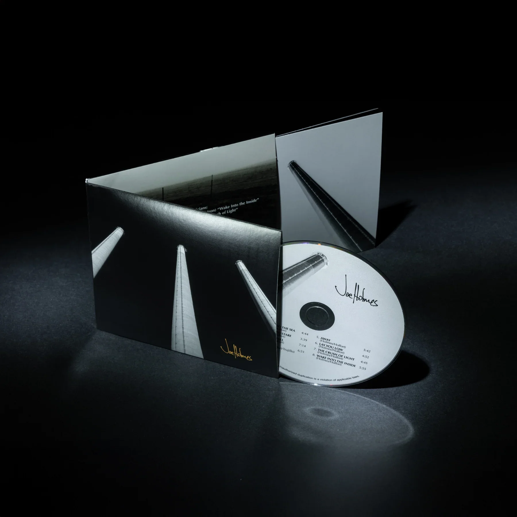 An album cover featuring a black background with geometric shapes and shadows, displaying the artist's name Joef Holmes and a song track list.