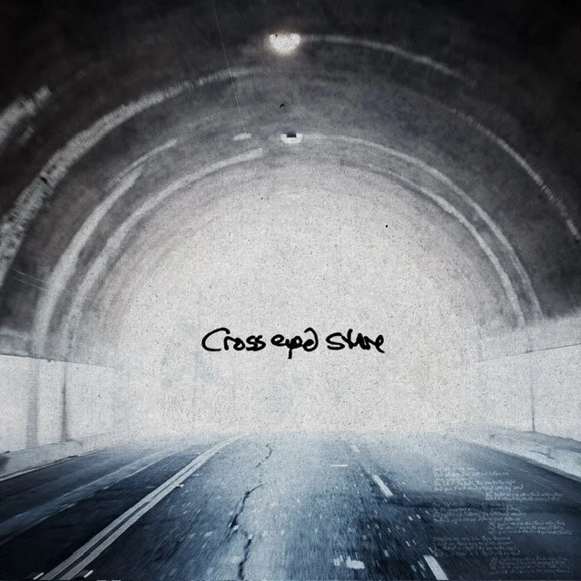 View of an empty tunnel with a road heading into it, with handwritten text on the tunnel wall that says 'Crossed Out'.