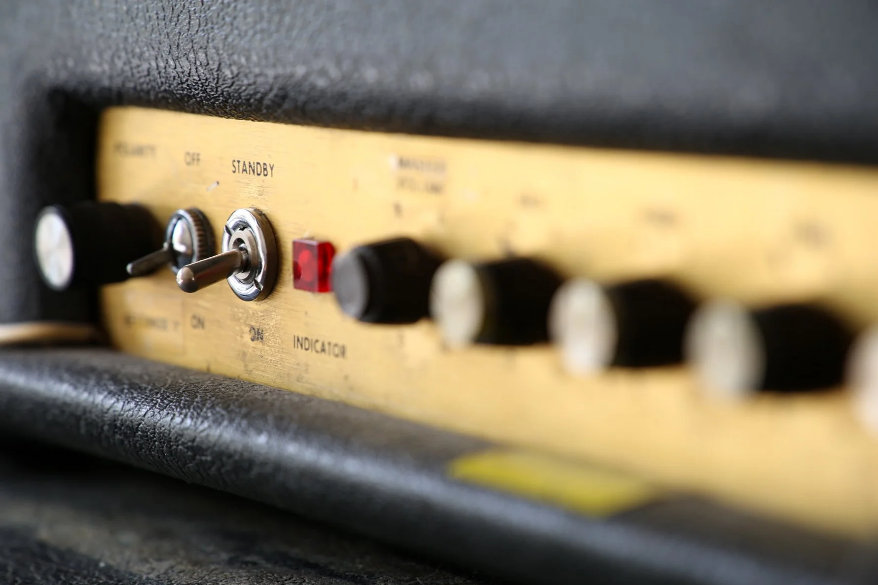 Close-up of a vintage guitar amplifier control panel with switches and knobs, including a switch marked 'STANDBY' and a red indicator light.