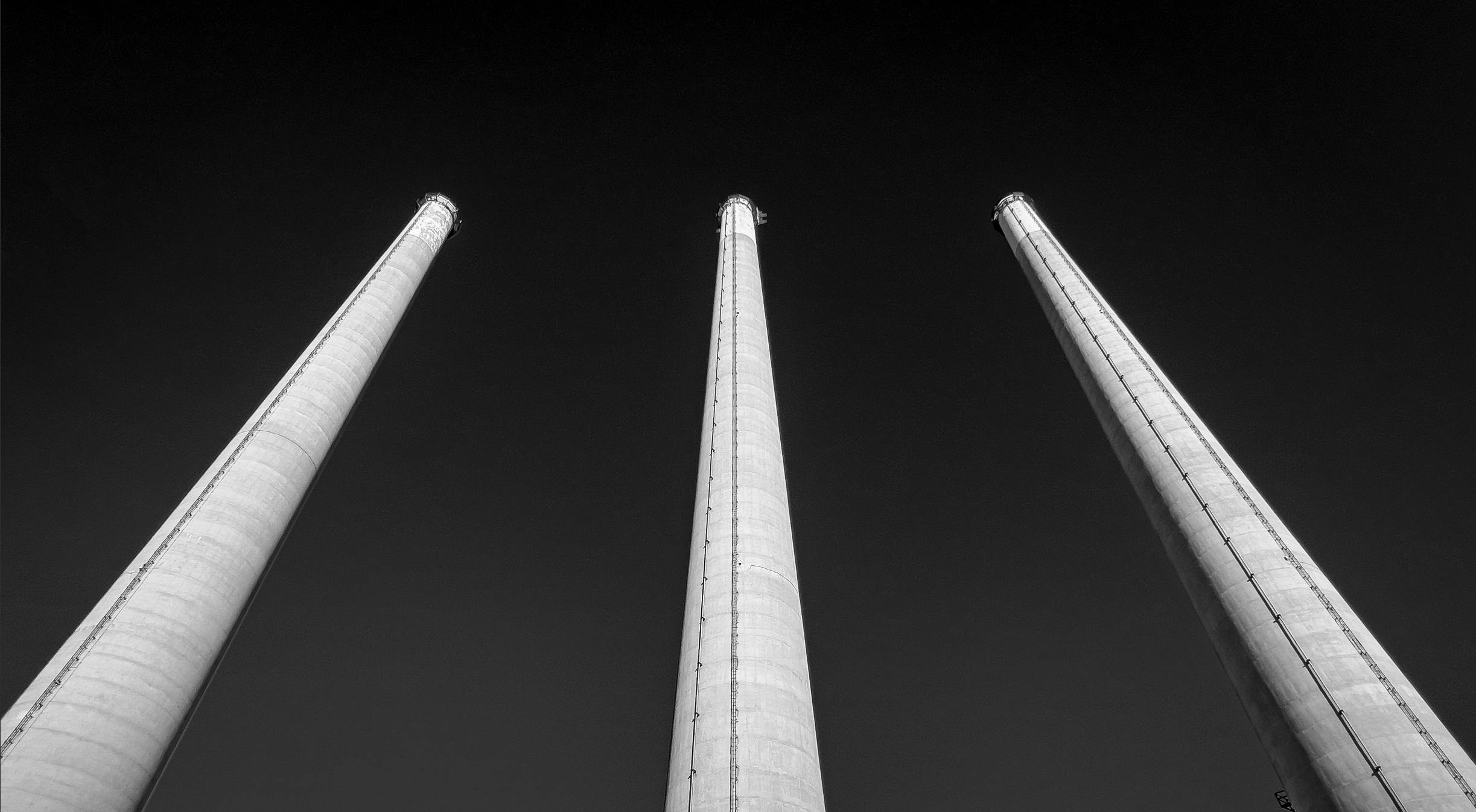 Three tall industrial smokestacks rising into a dark night sky.