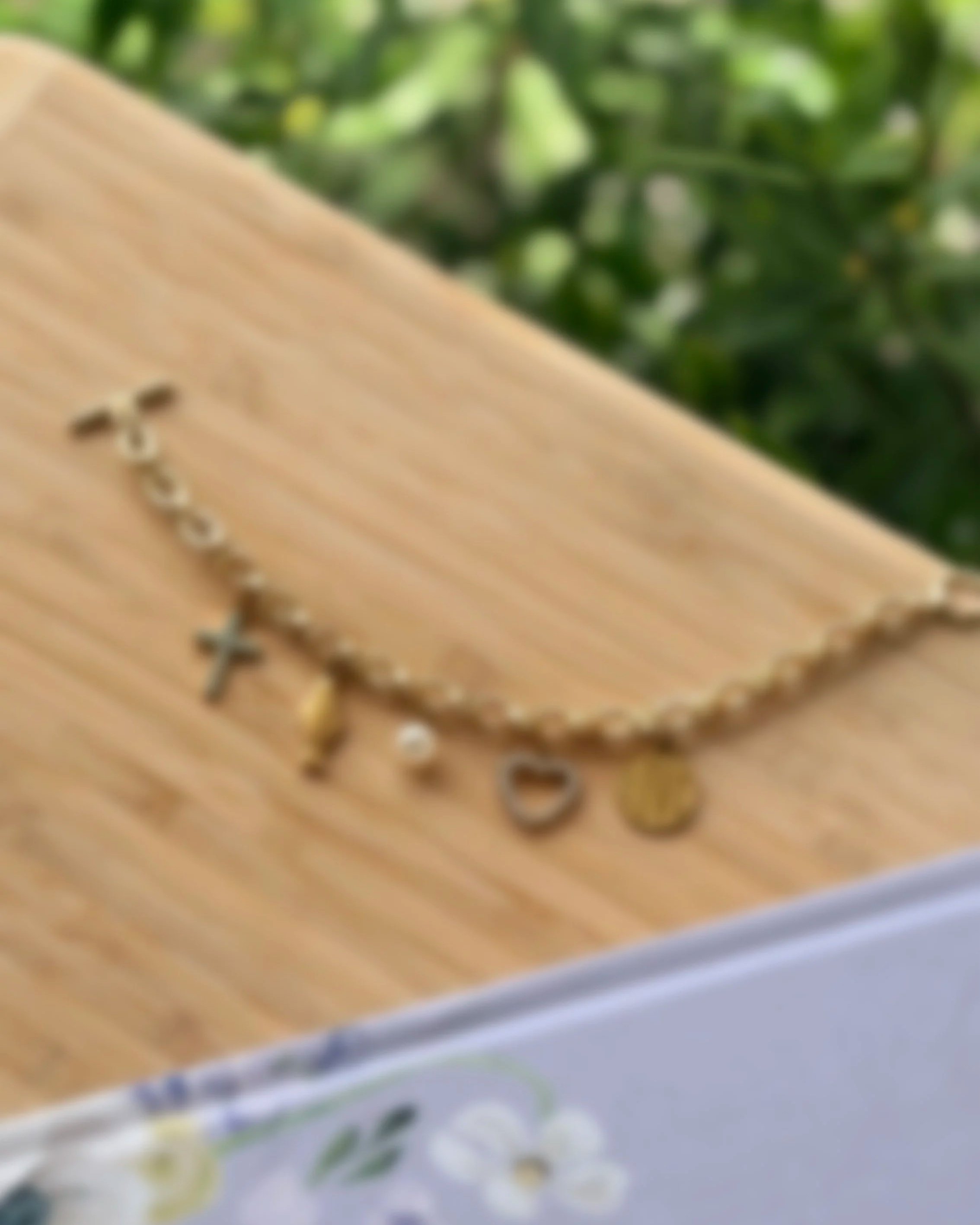 gold Christian charm bracelet with cross and faith charms on wood background