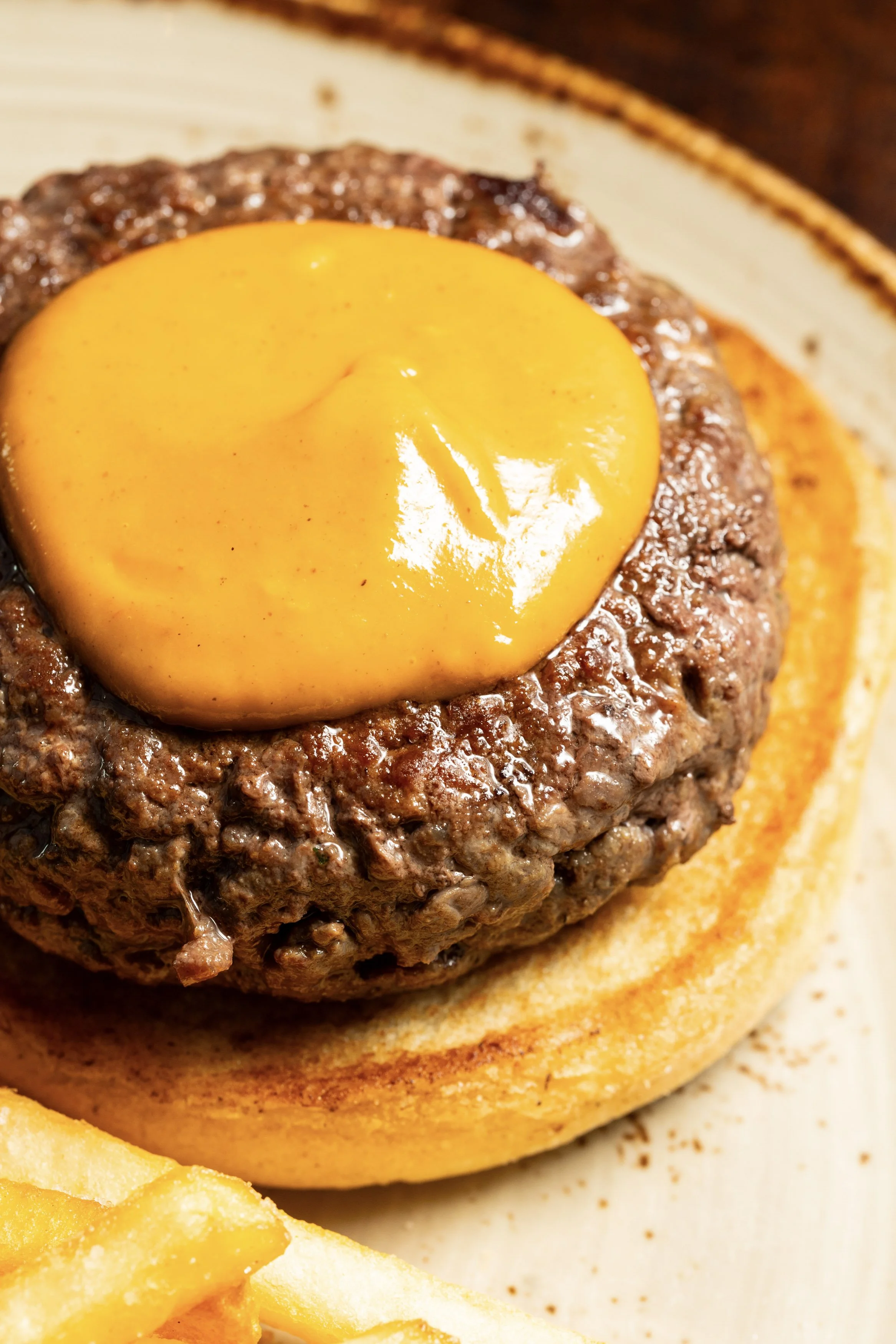 Close-up of a cheeseburger with a beef patty topped with melted cheddar cheese on a toasted bun.