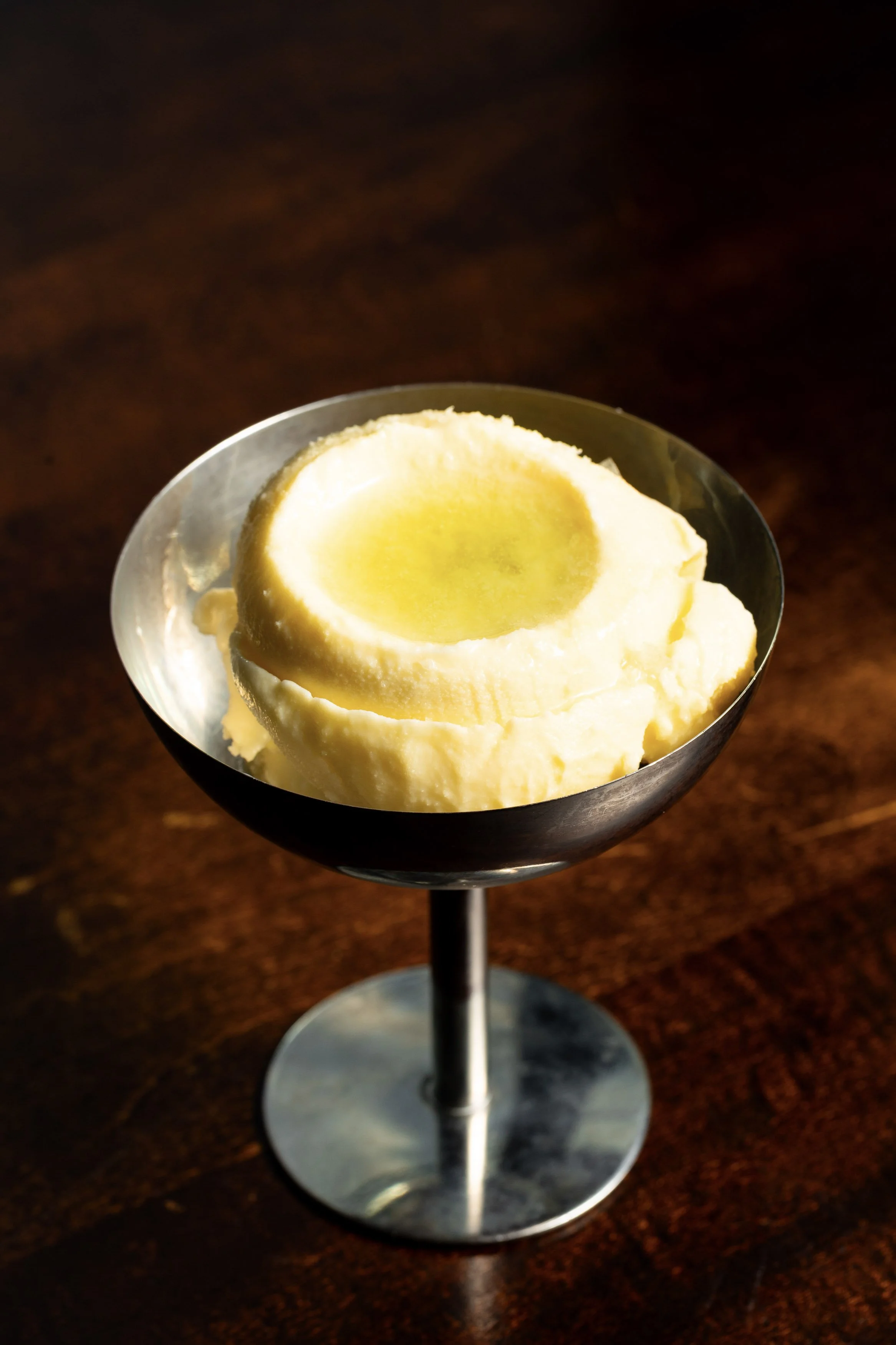 A scoop of vanilla ice cream in a metal dessert glass
