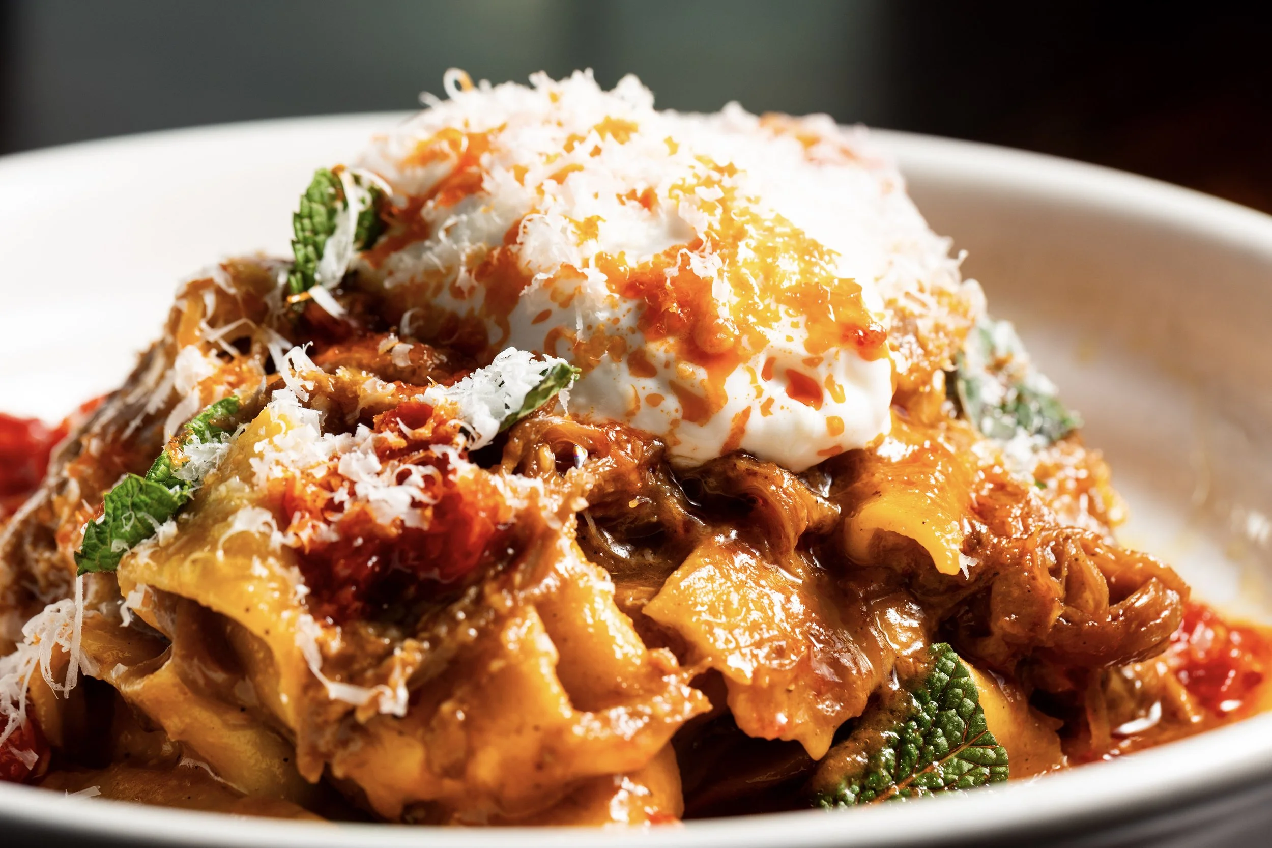Close-up of an Indian curry dish with rice, topped with a poached egg, grated cheese, and garnished with green herbs.