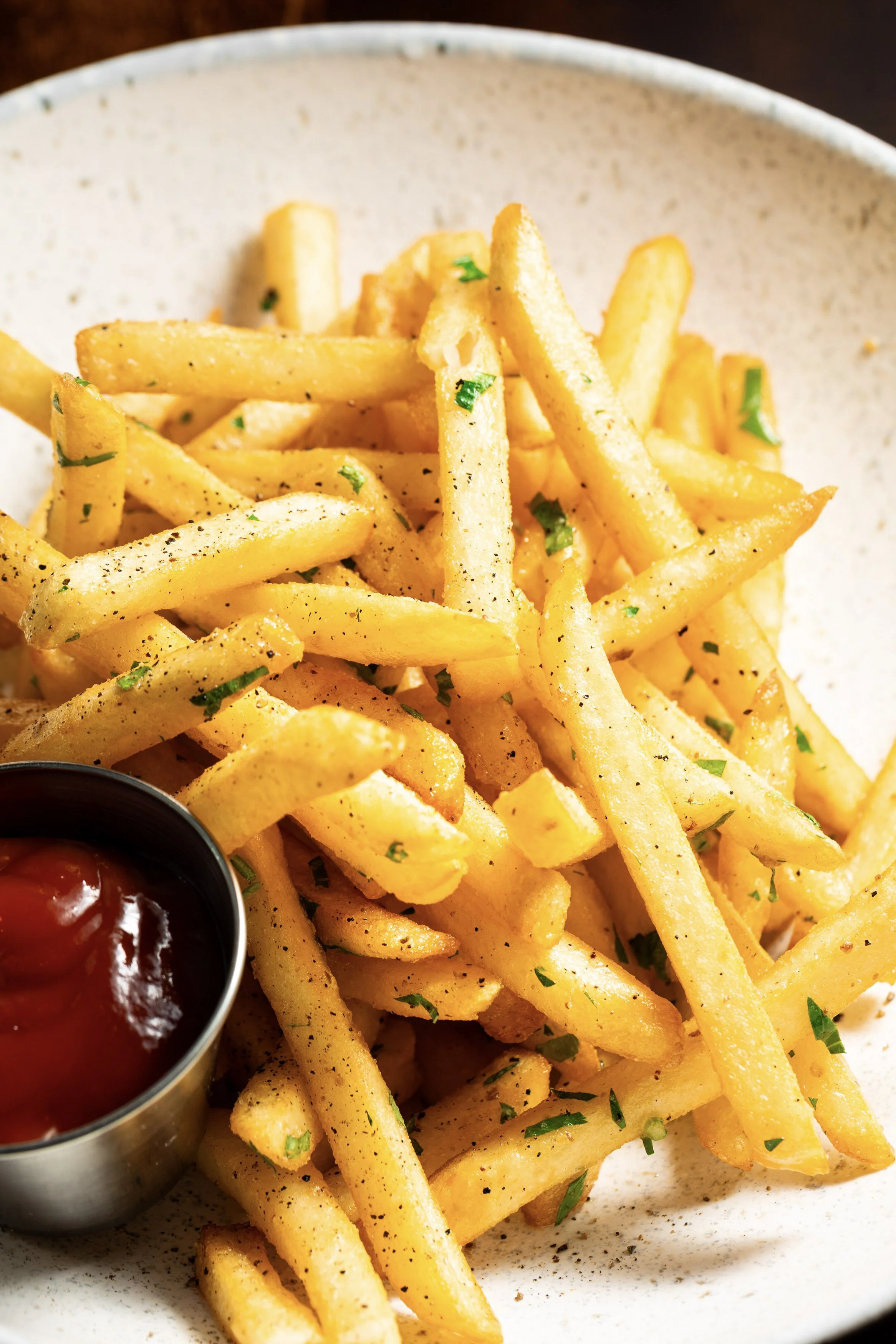 French fries with chopped parsley, served with ketchup in a metal cup