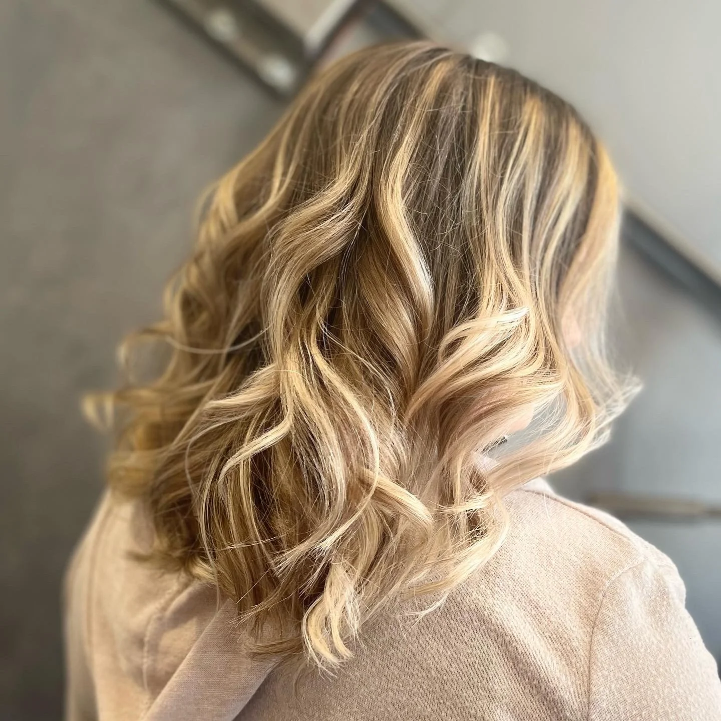 Close-up of a woman with shoulder-length blonde hair styled in loose curls.