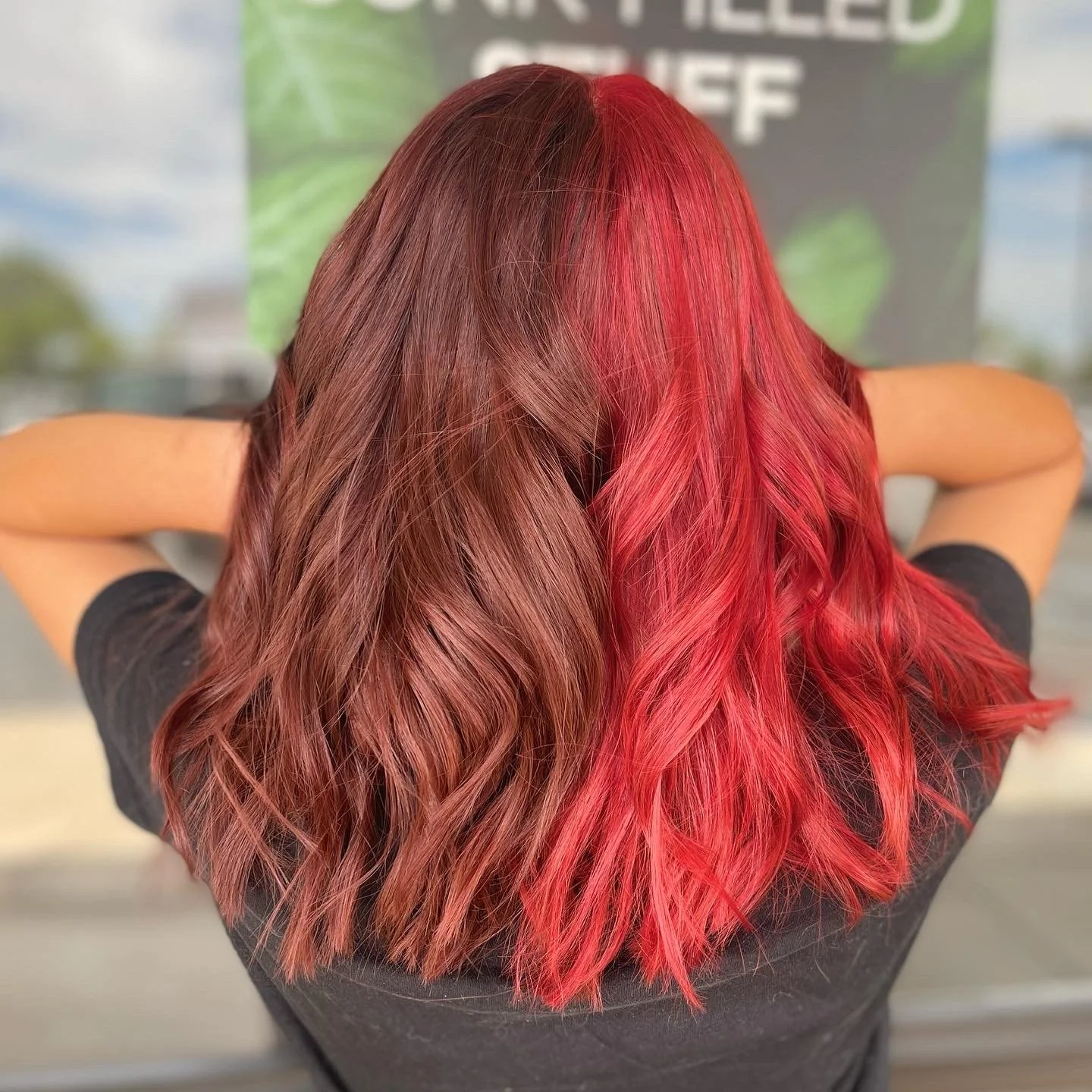 Back of a woman with wavy hair, half of which is dyed red and half natural brown.