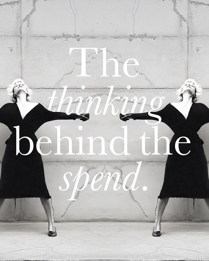 Black and white photo of a woman in a black dress with her arms outstretched, standing against a concrete wall. Text overlay reads, "The thanks behind the spend."