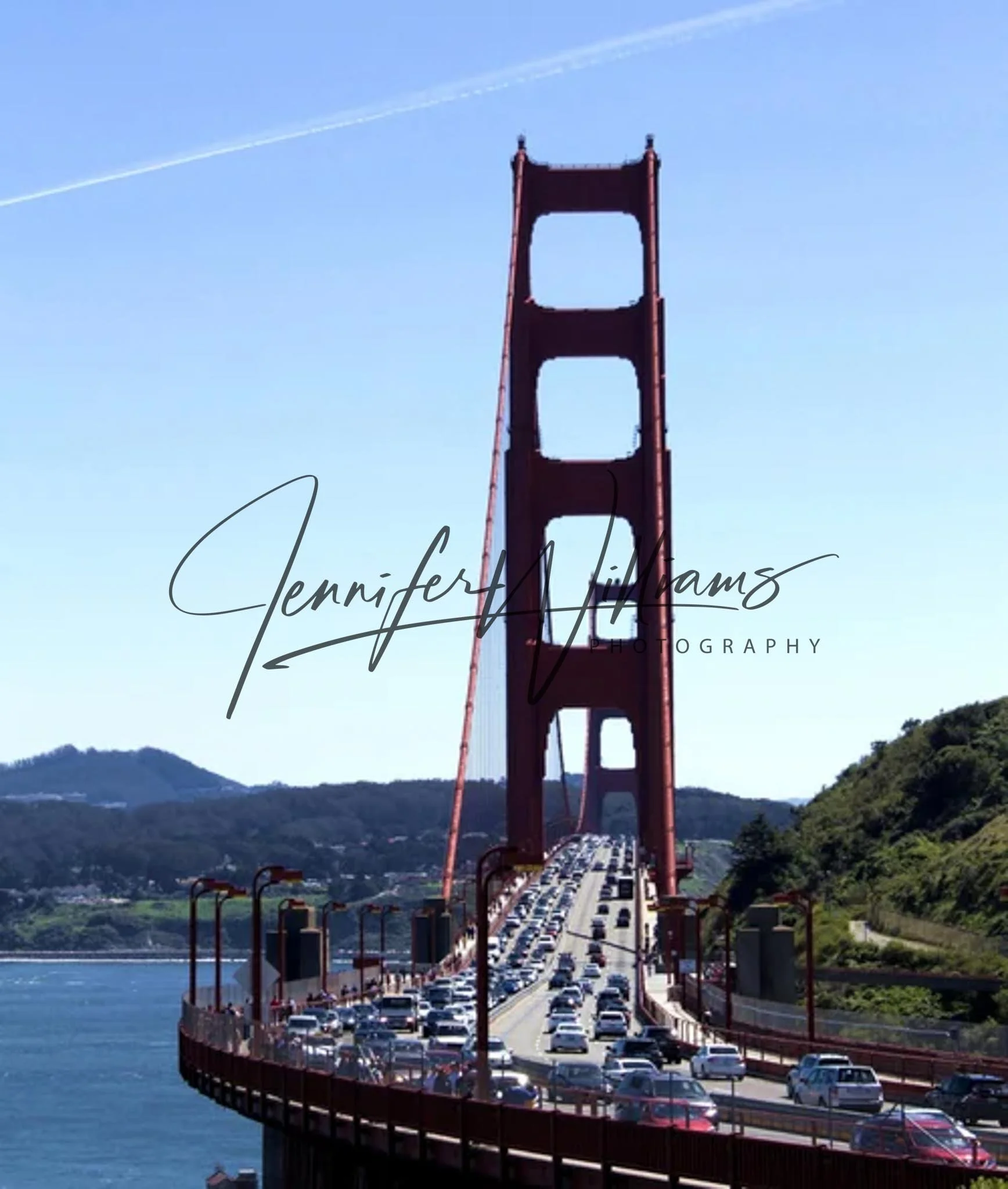 The Golden Gate Bridge in San Francisco with traffic on the bridge and green hills in the background under a clear blue sky.