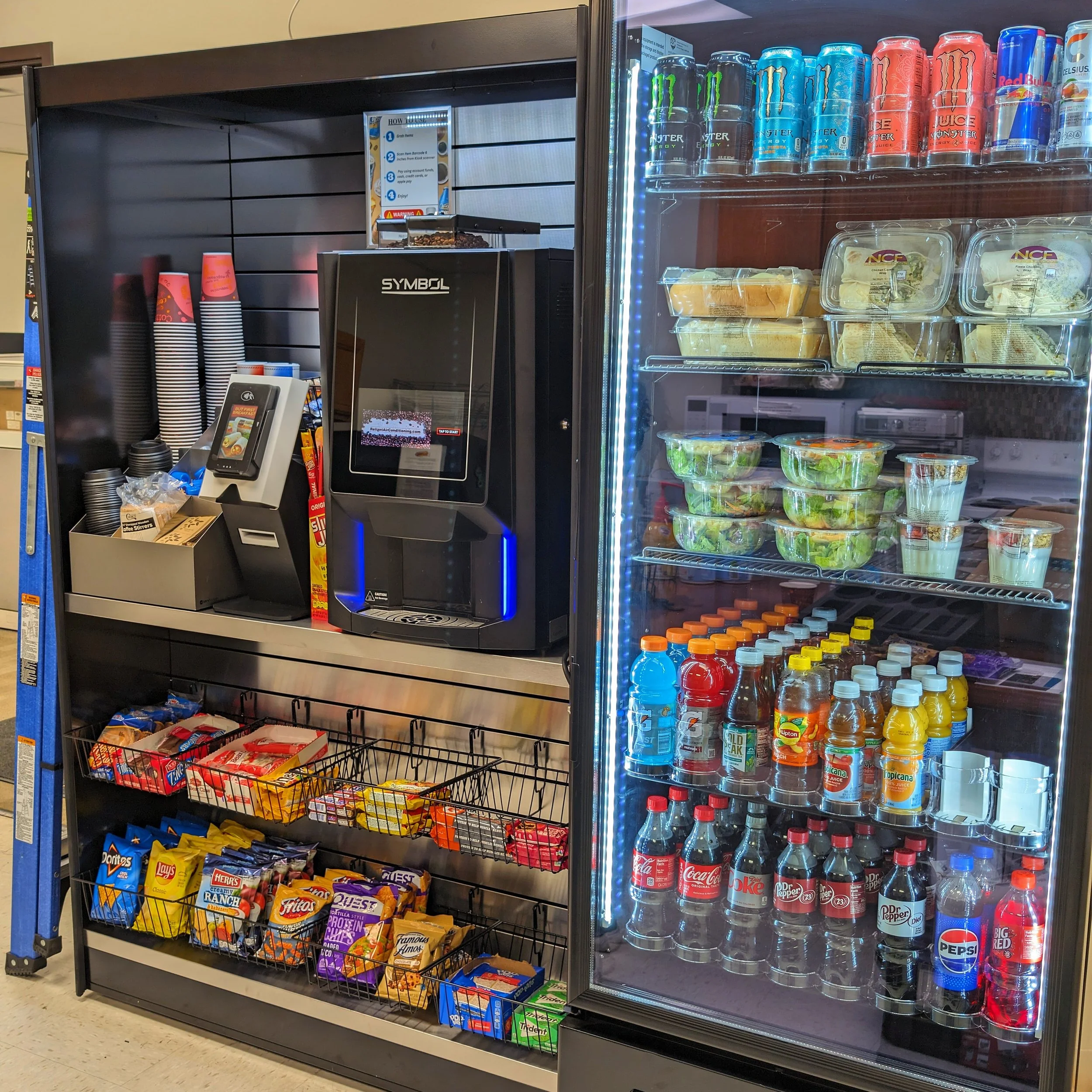 Snack and beverage display case with candy, chips, and soda bottles inside a convenience store.
