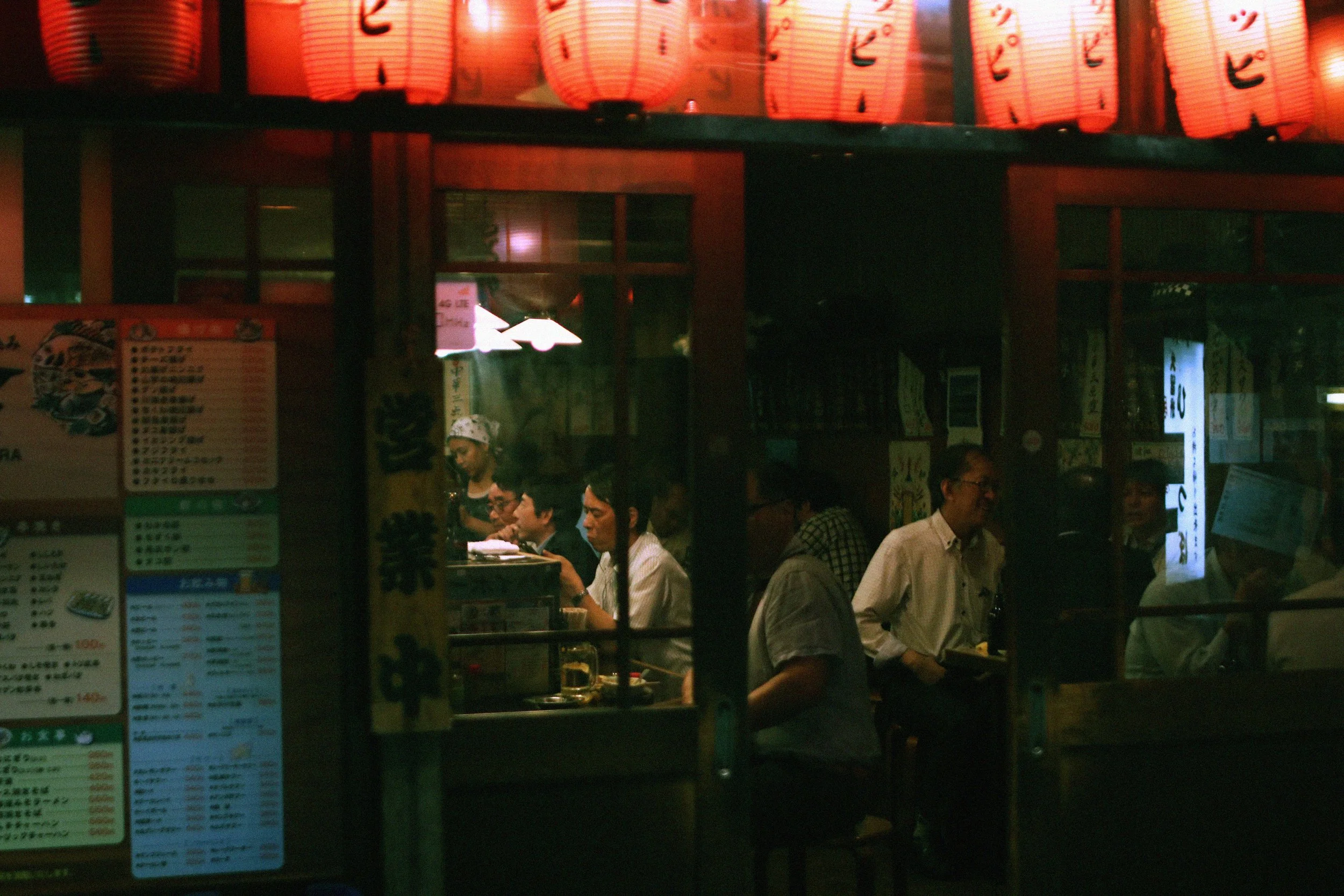 People dining inside a Japanese restaurant illuminated by red paper lanterns