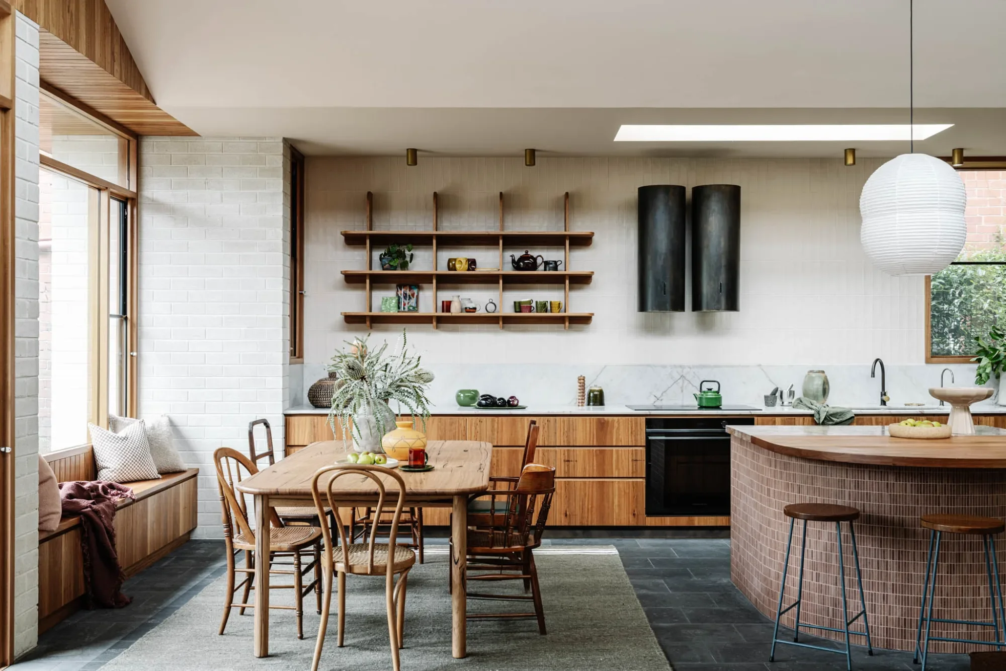 Kitchen at Carlton House with open timber shelving and a curved, tiled island bench