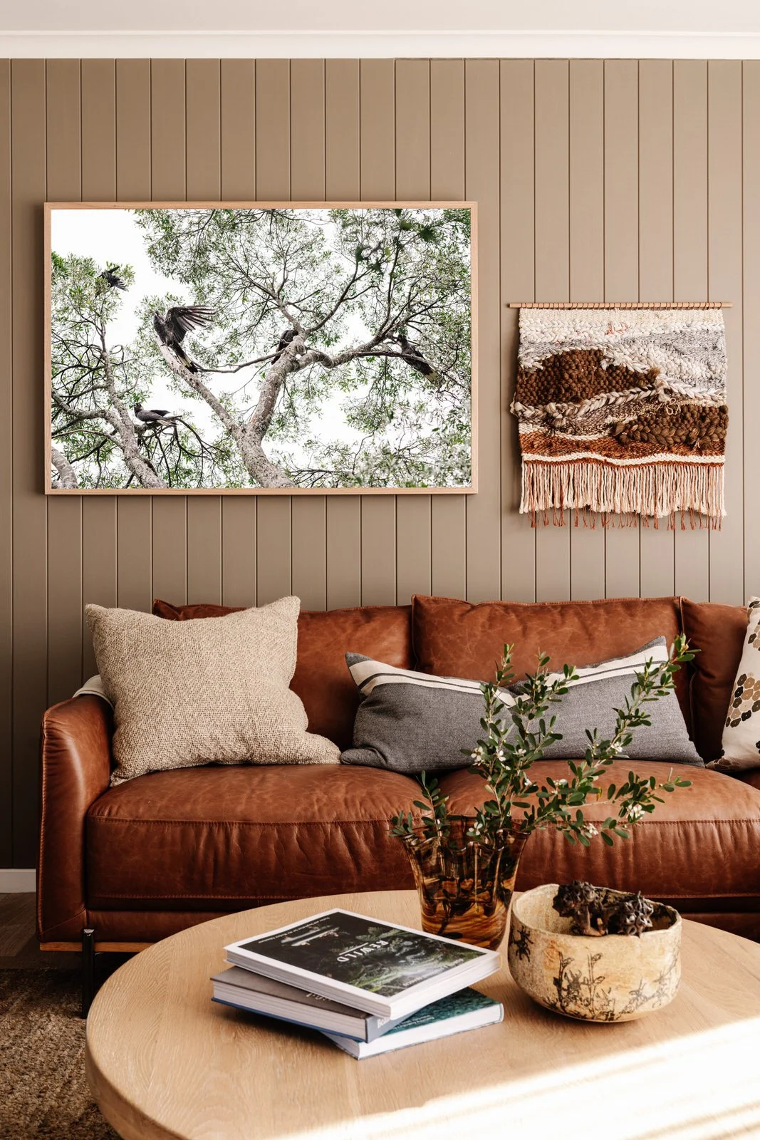 Black Cockatoos print above a tan leather sofa