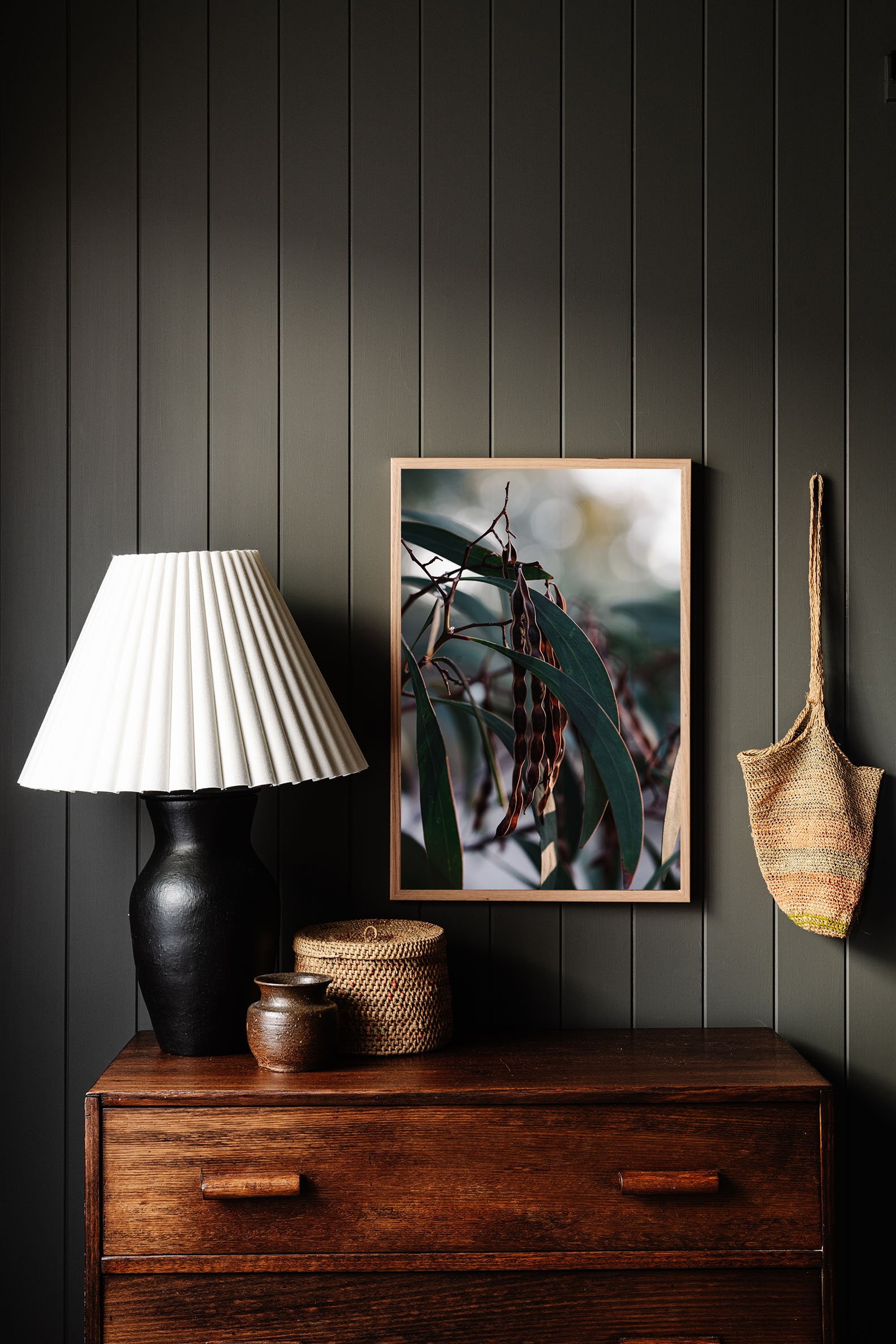 Seed Pods and Eucalyptus print on a timber dresser beside a lamp