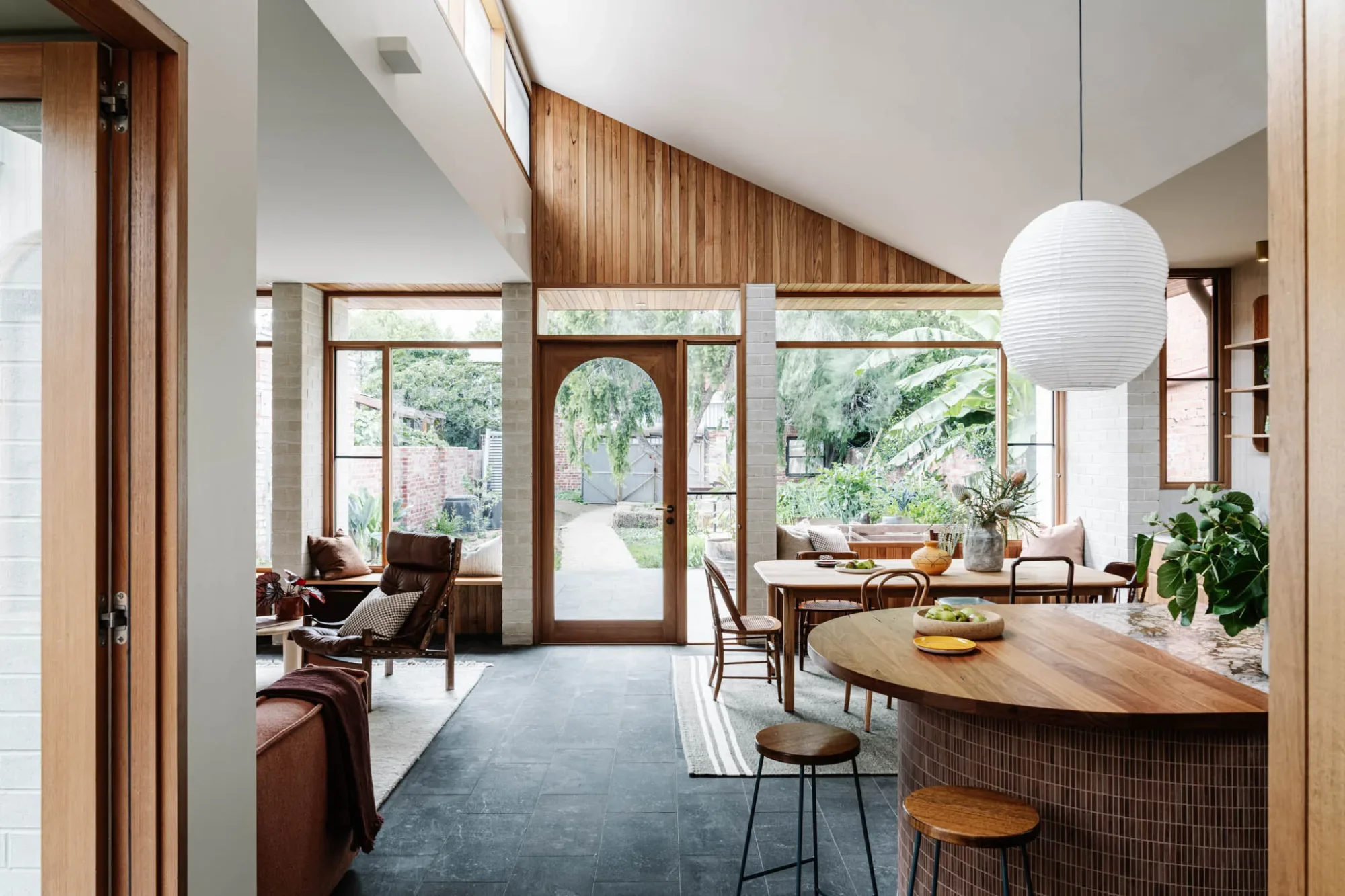 Carlton House living and dining area, with a timber-lined gable and an arched door out to the garden