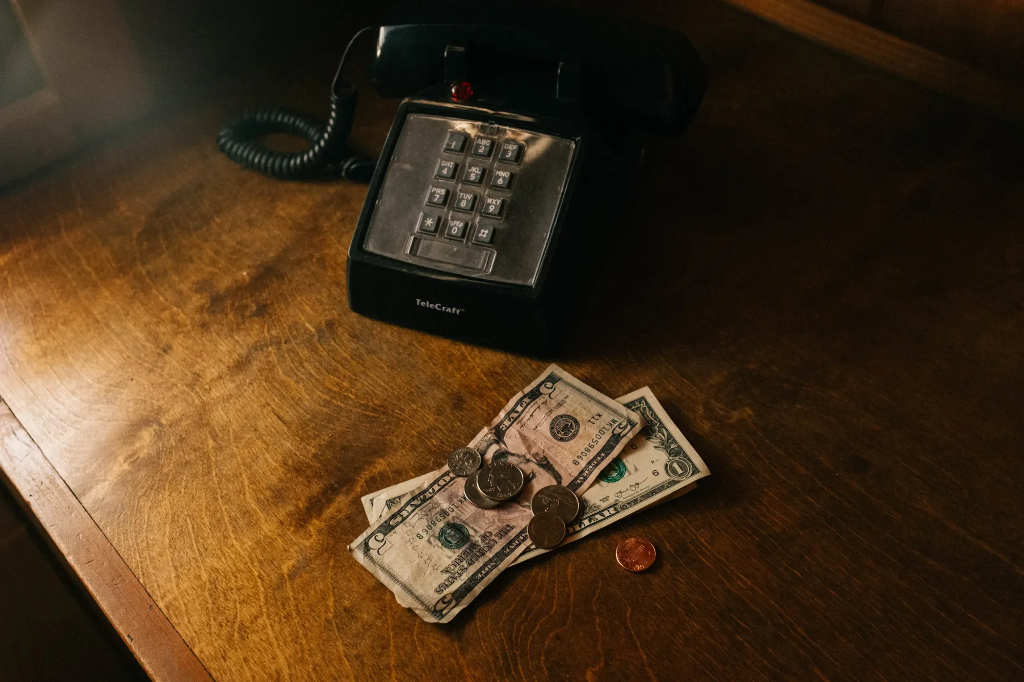 Desk phone with banknotes and coins on a timber table
