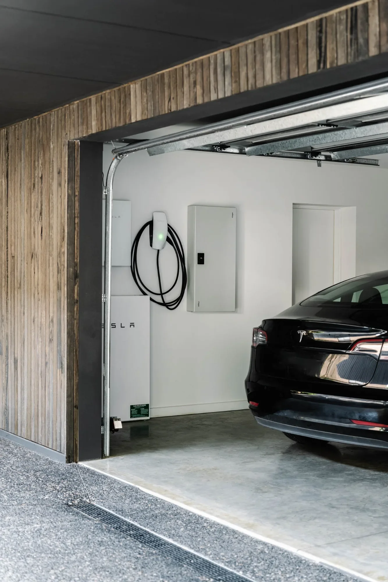 Electric car parked in a timber-clad garage with a wall-mounted charger