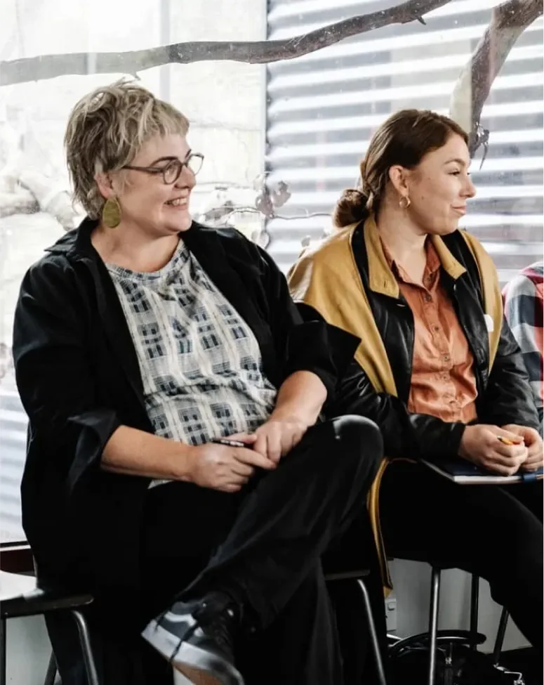 Two women smiling and listening together during a coaching session.