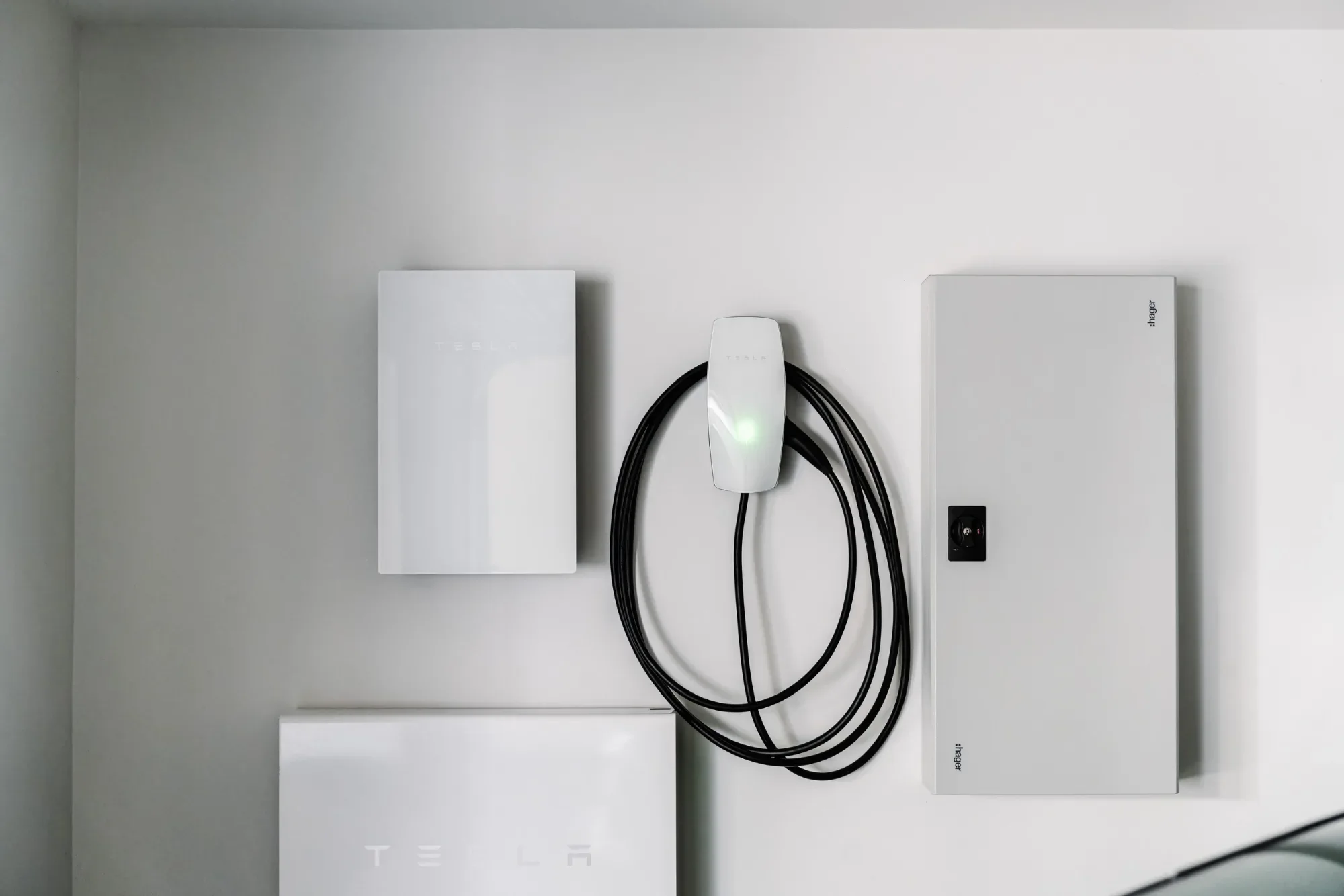 Electric car charger and cable mounted on a white garage wall