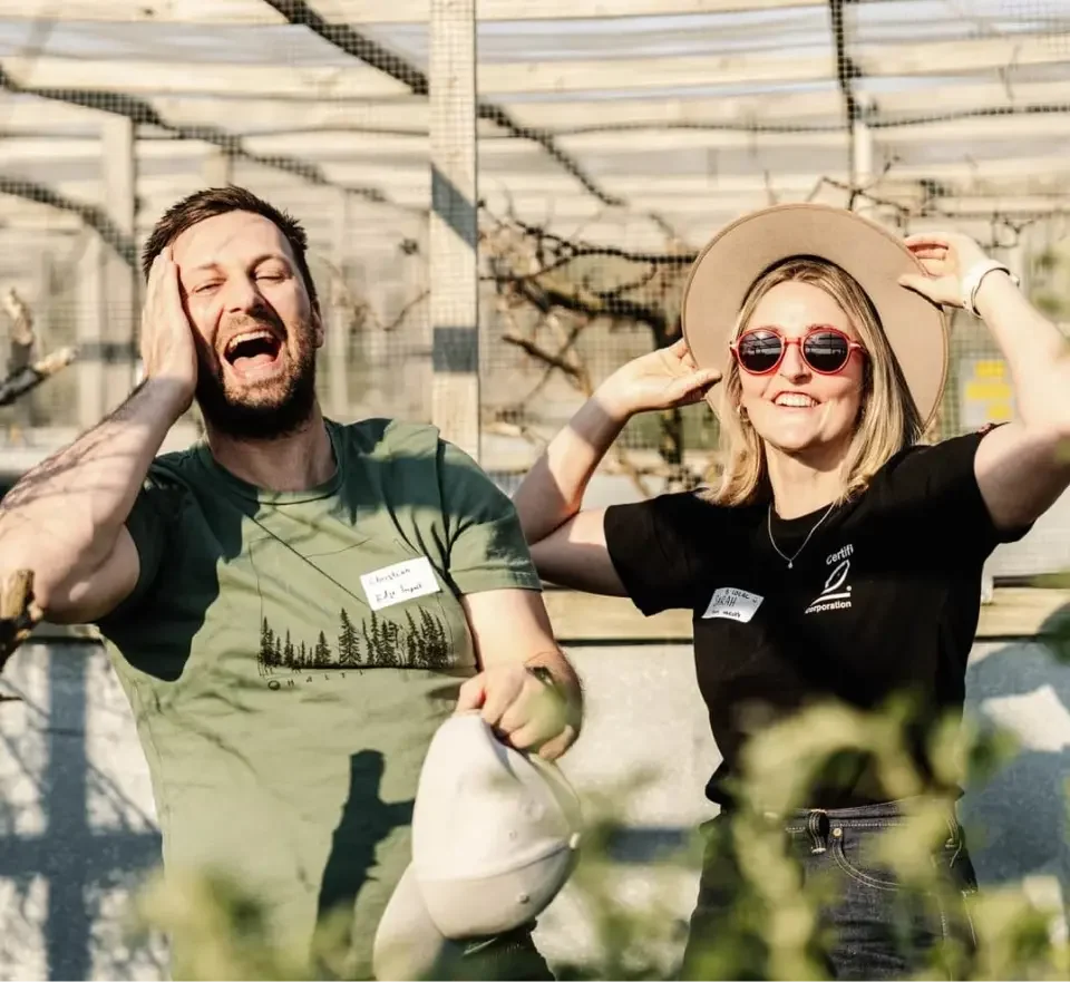 Man laughing alongside a woman outdoors at a community event, both wearing name tags.
