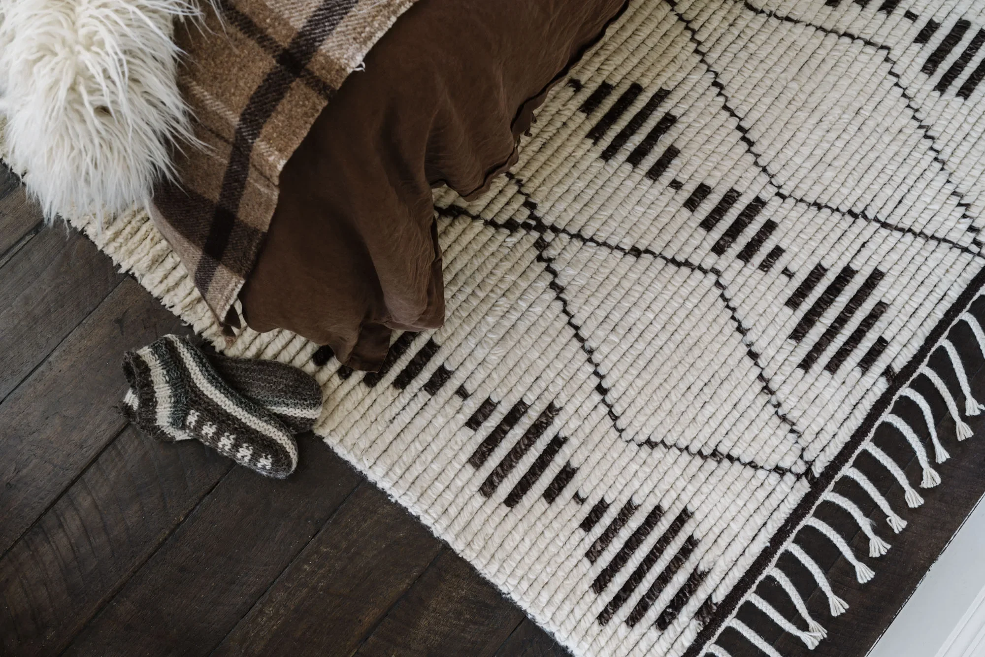 Black and cream patterned Armadillo rug with a fringed edge on a dark timber floor