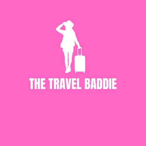 Silhouette of a woman with a suitcase on a pink background, with the text "The Travel Baddie".