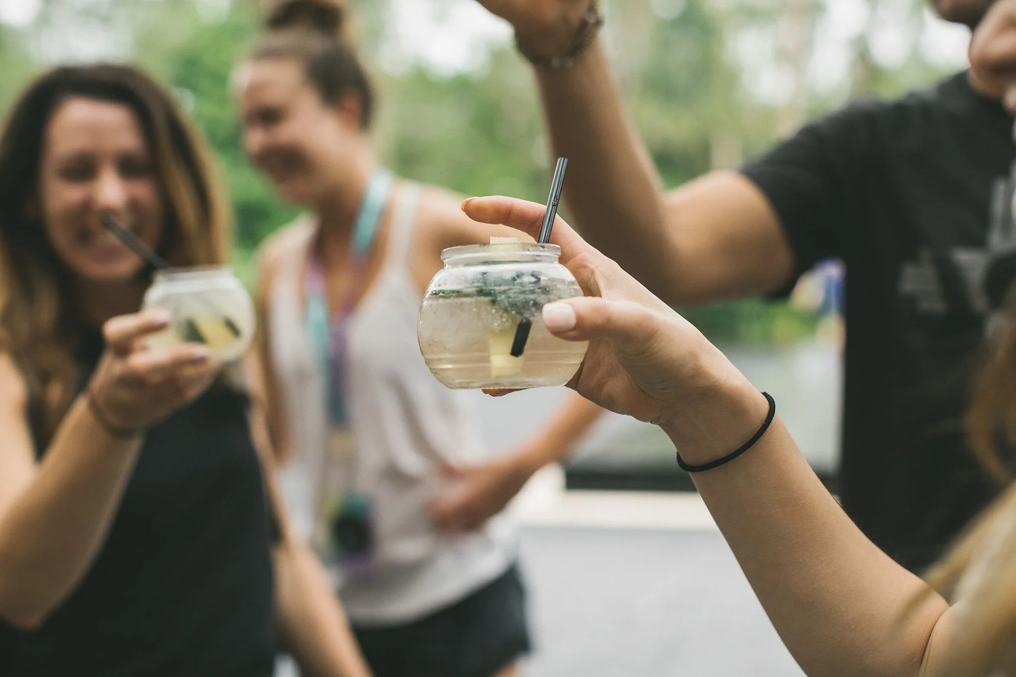 People holding jars with drinks in a social outdoor setting