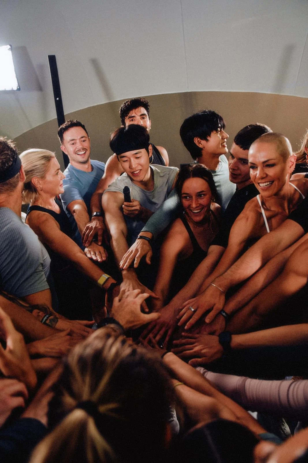 A group of people participating in a team-building activity, all putting their hands together in the center.