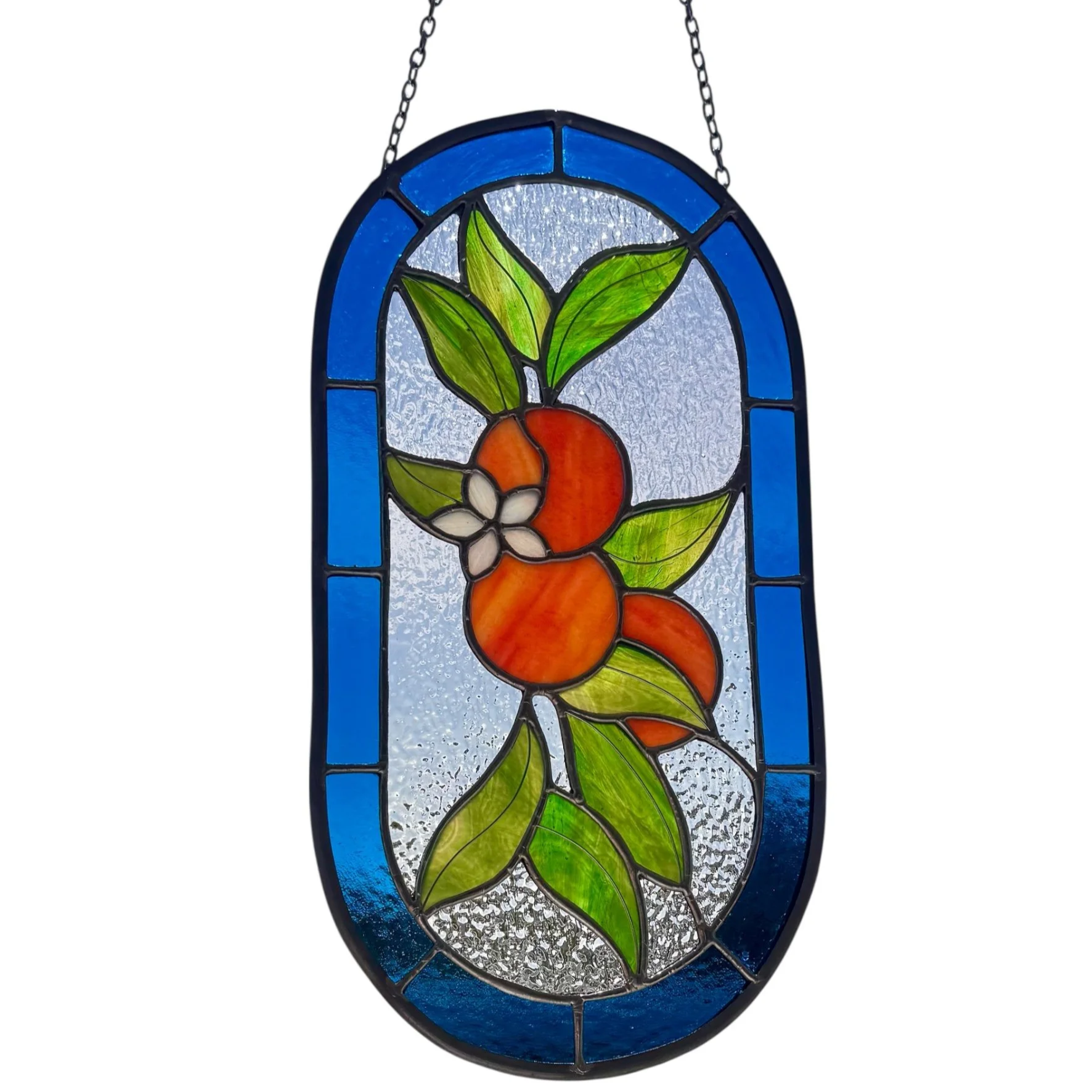 Stained glass window with orange fruit, green leaves, and white flowers, framed by a blue border.