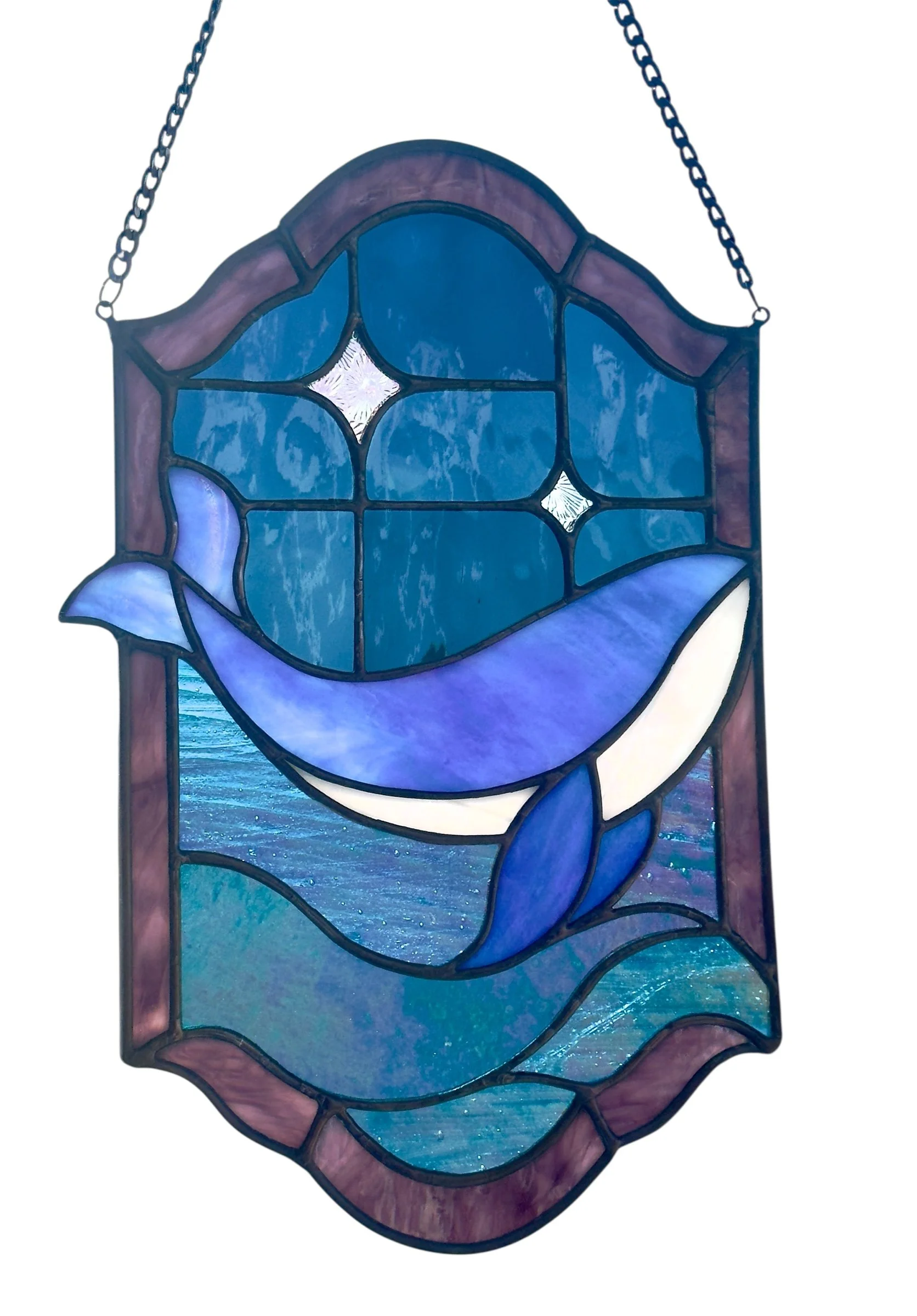 Stained glass artwork depicting a blue whale with water and starry night sky background.
